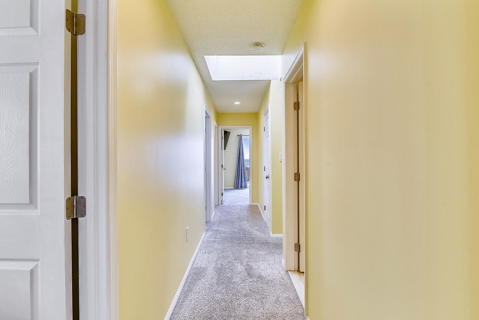 Natural light pours through the skylight above, brightening your path to restful bedrooms and private spaces throughout this welcoming home.