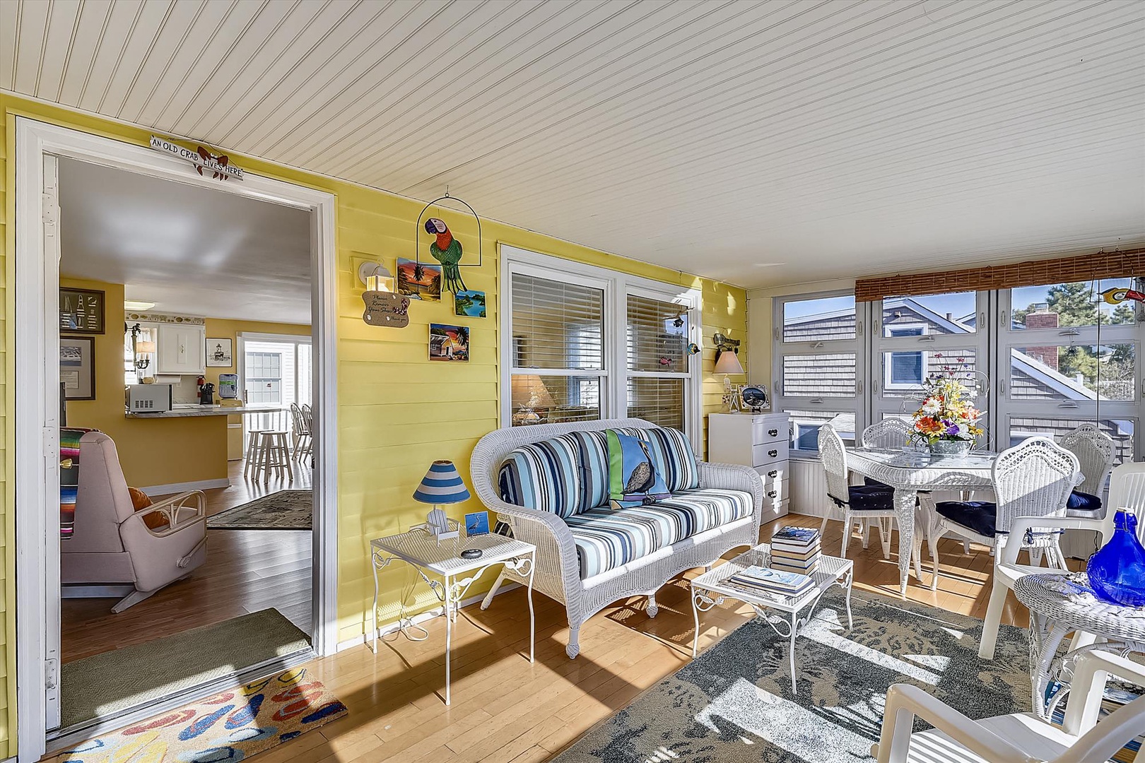 Sunlight streams through large windows filling your bright sunroom with coastal charm, where cheerful yellow walls and nautical-striped seating invite you to unwind and soak in your peaceful home-away-from-home.