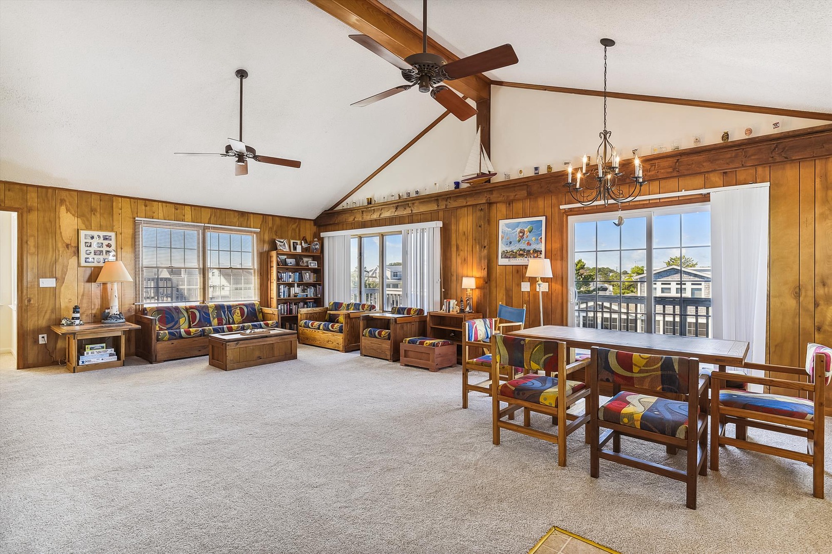Imagine yourself relaxing in this spacious, sunlit living area with vaulted ceilings, warm wood accents, and vibrant seating. Large windows frame stunning views, perfect for your peaceful coastal retreat.