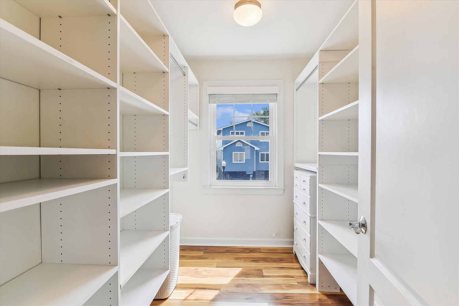 A bright, organized walk-in closet with custom shelving on both sides and built-in drawers, giving you plenty of room to keep your wardrobe tidy and accessible.
