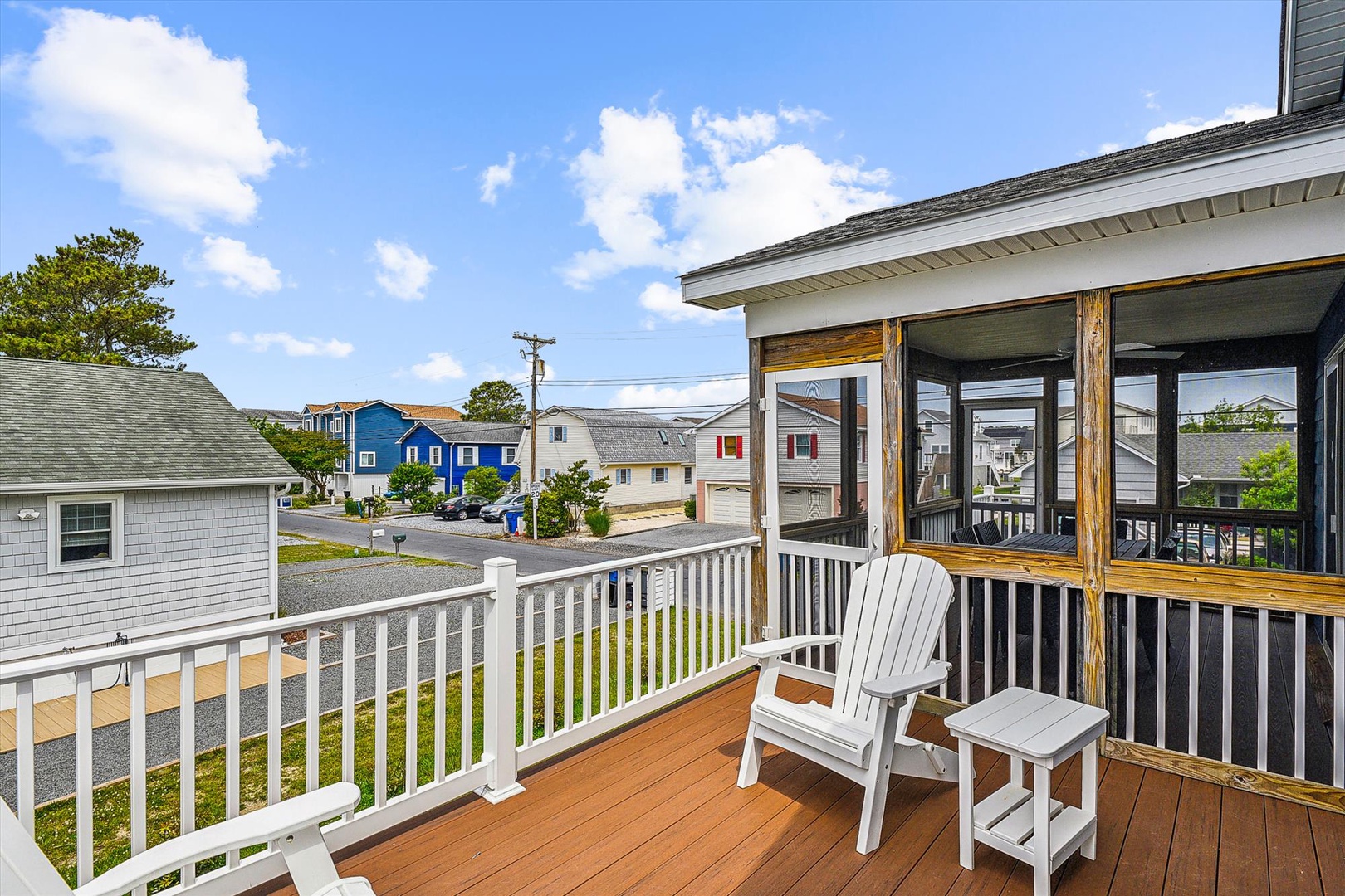 Charming residential neighborhood visible from the property's deck, featuring colorful beach houses and tree-lined streets in a peaceful coastal community setting.