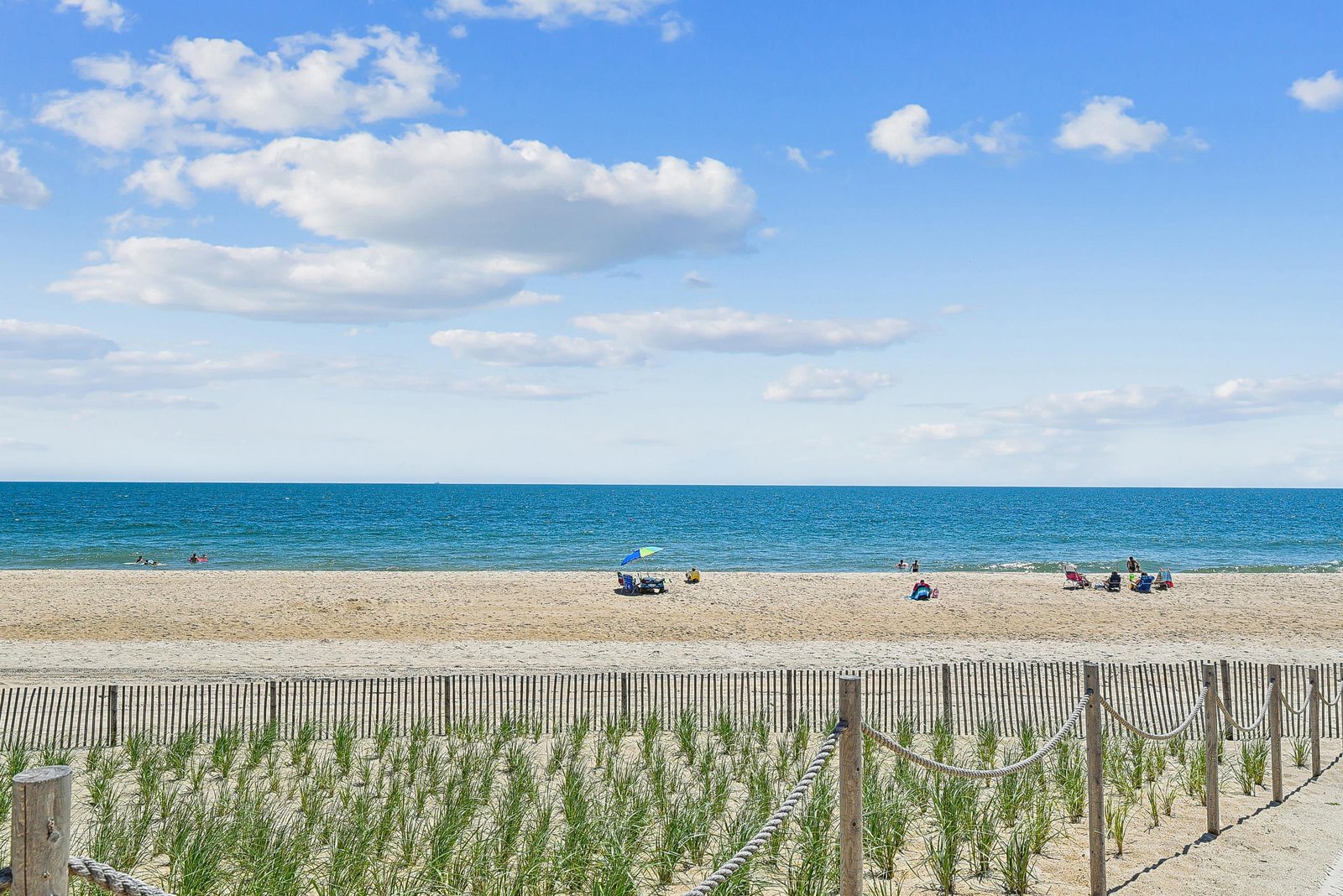 Sandy beach with calm blue waters stretches along the coastline, offering a peaceful seaside escape.