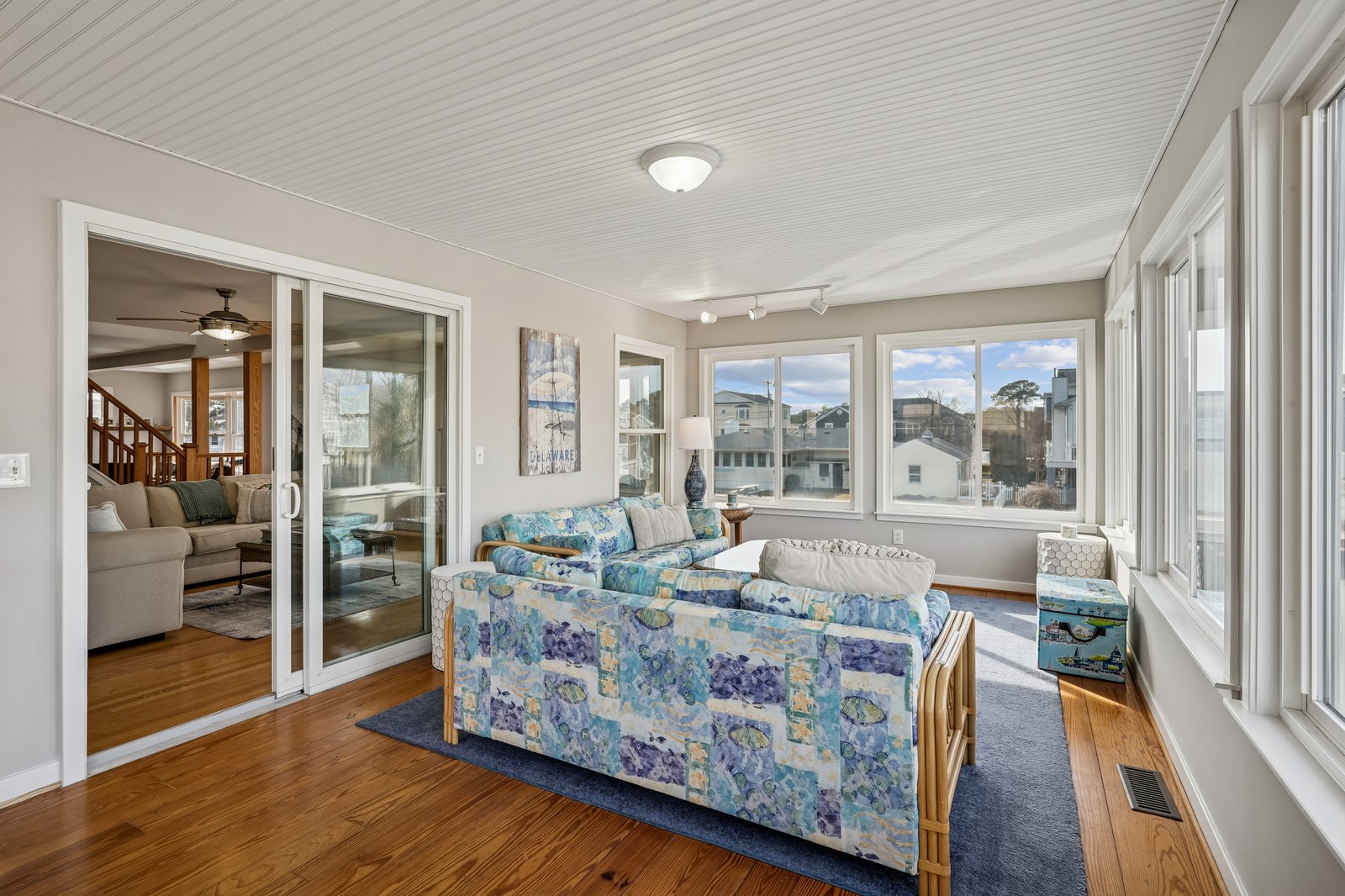 Relax in your bright sunroom with panoramic windows and cheerful blue furniture, perfect for morning coffee or afternoon reading.