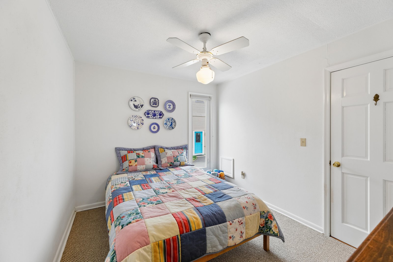 Settle in for a restful night in this cozy bedroom, where a cheerful patchwork quilt and charming wall décor create a warm, inviting space perfect for your stay.