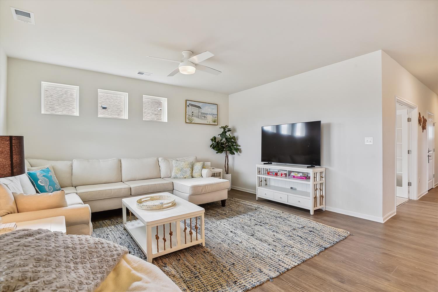 Settle into your spacious living room with plush sectional seating, modern entertainment center, and coastal touches that make unwinding effortless.