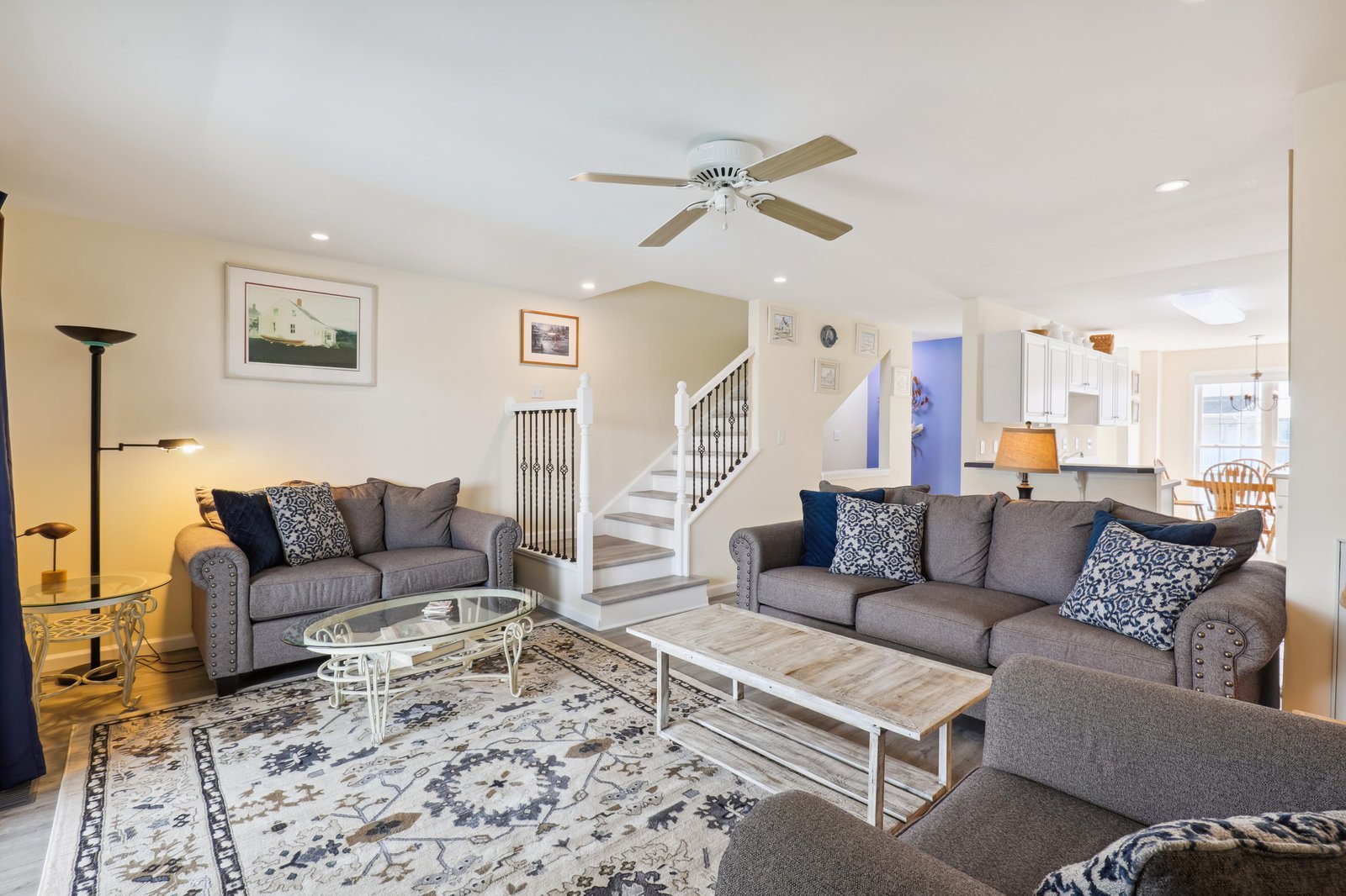Relax into plush gray seating, unwind beneath the soft glow of the ceiling fan, and enjoy an inviting open layout perfect for your coastal getaway.
