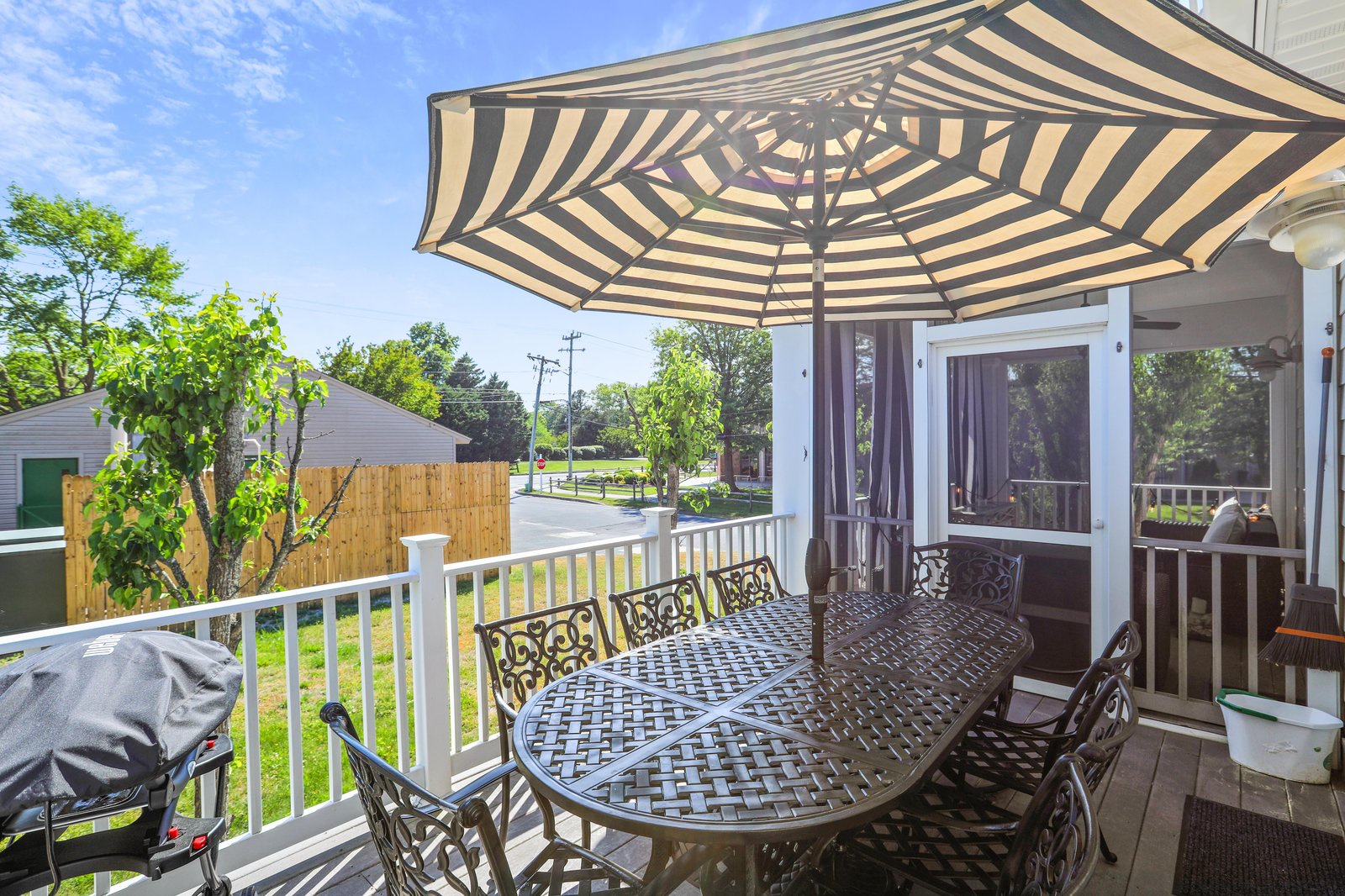 A spacious covered deck with dining for eight beneath a cheerful striped umbrella—your perfect spot for morning coffee or sunset dinners in the fresh air.