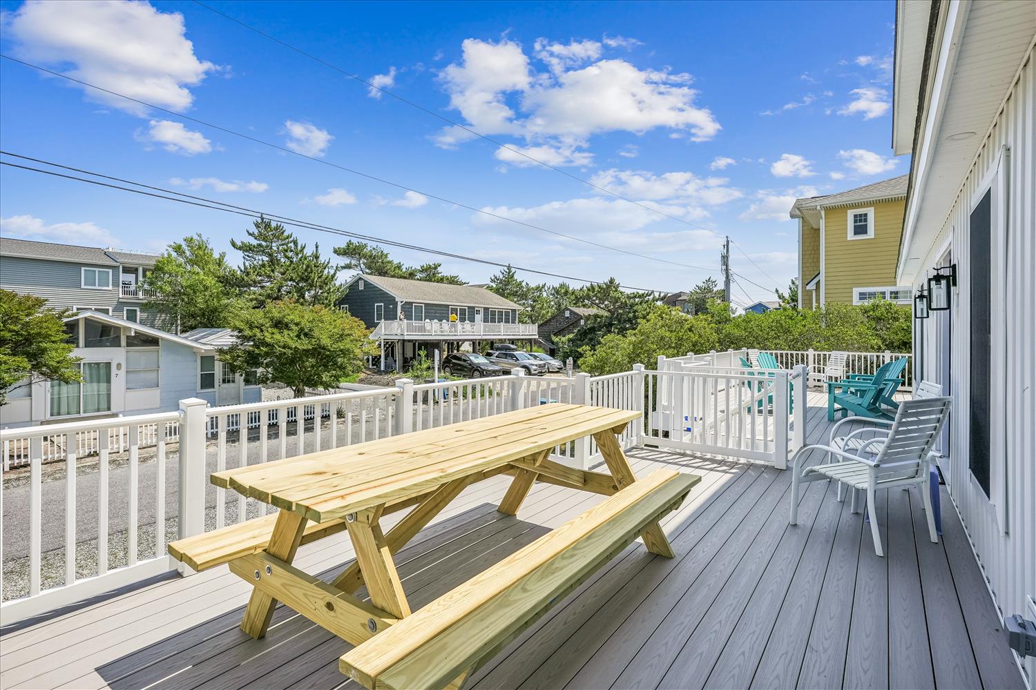 The property is located in a residential beach neighborhood with neighboring homes and nearby trees, offering a quiet coastal setting for your stay.