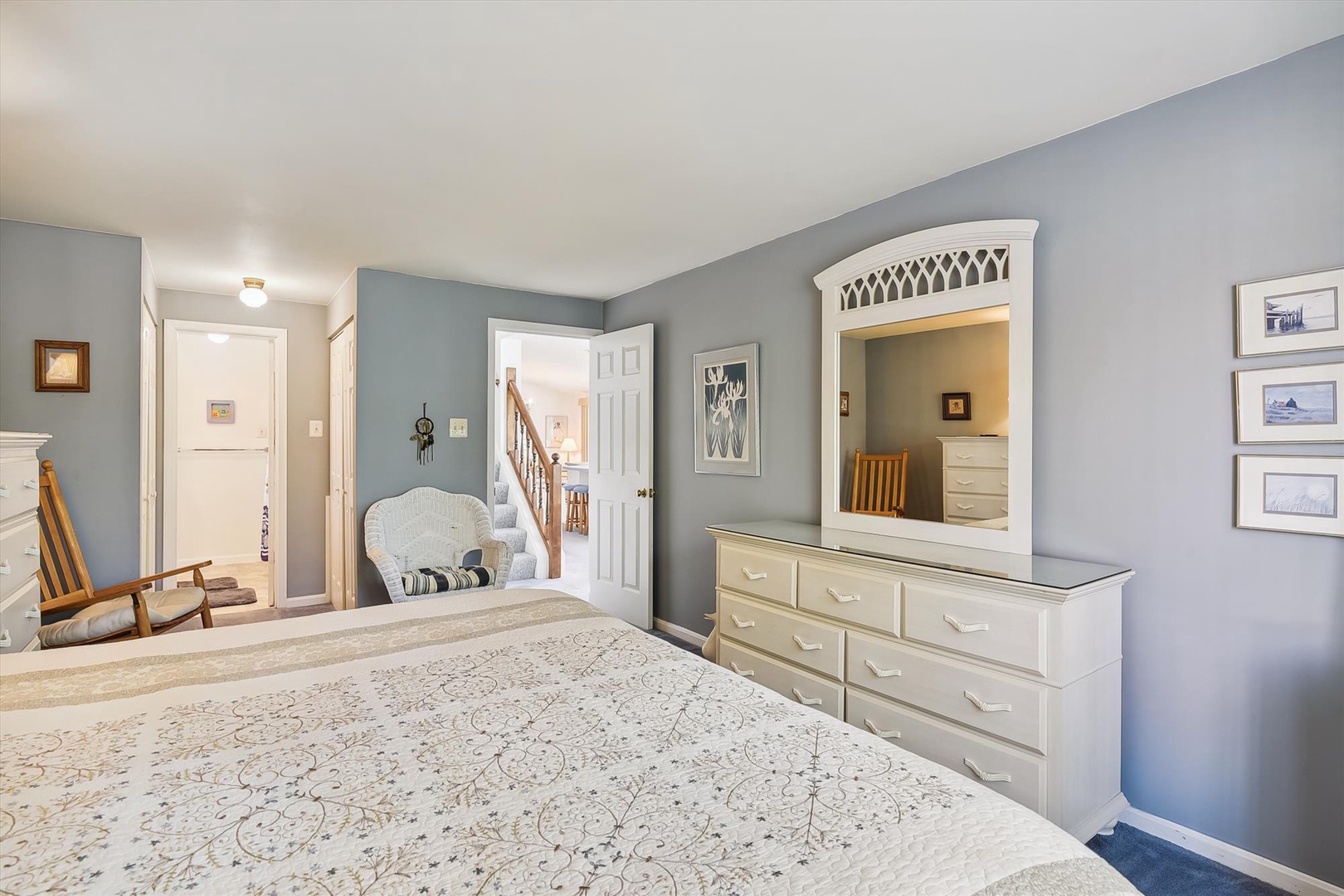 Unwind in your serene retreat featuring soft blue-gray tones, a cozy rocking chair, and ample dresser space—your perfect escape after a day of exploring.