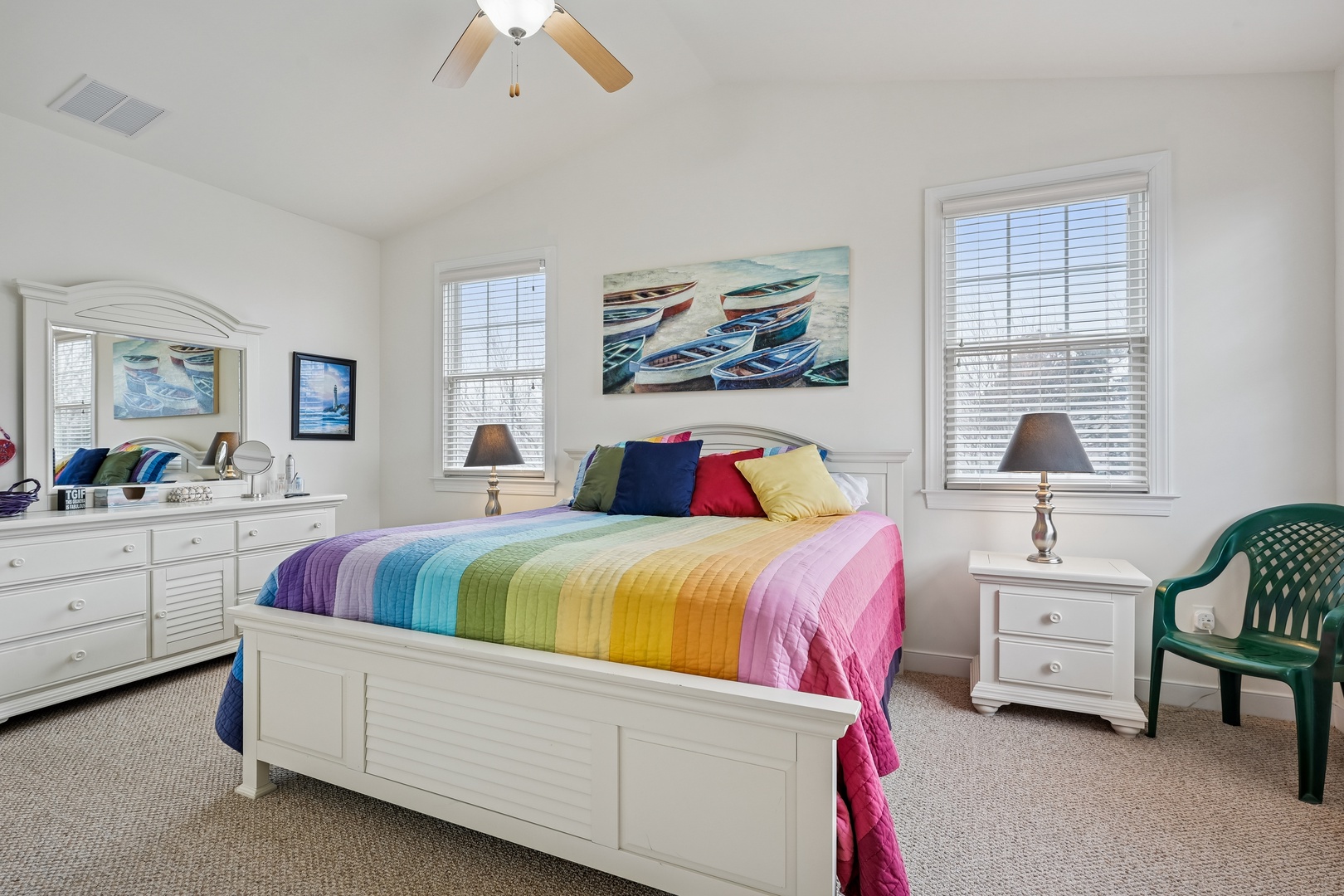 Drift into peaceful sleep surrounded by cheerful rainbow bedding and coastal artwork in your bright, welcoming bedroom.