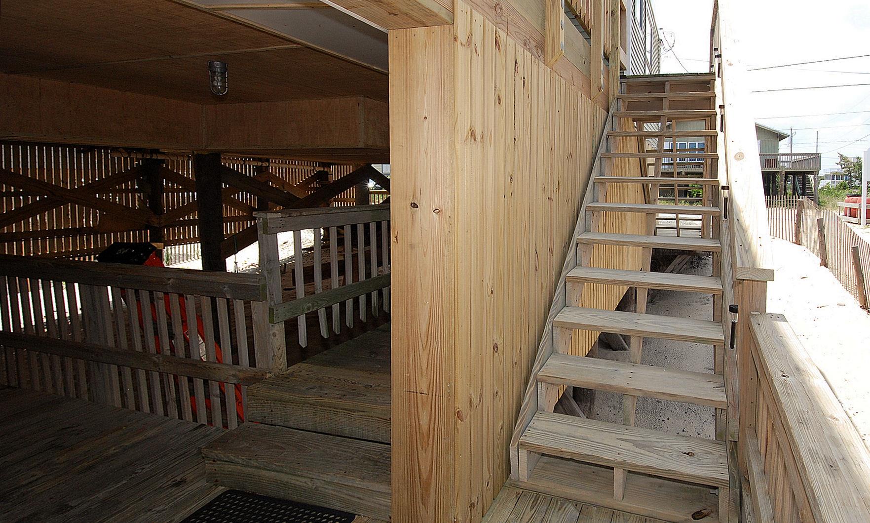 The elevated deck and stairway provide easy access to the property, with covered parking below offering convenient outdoor storage.