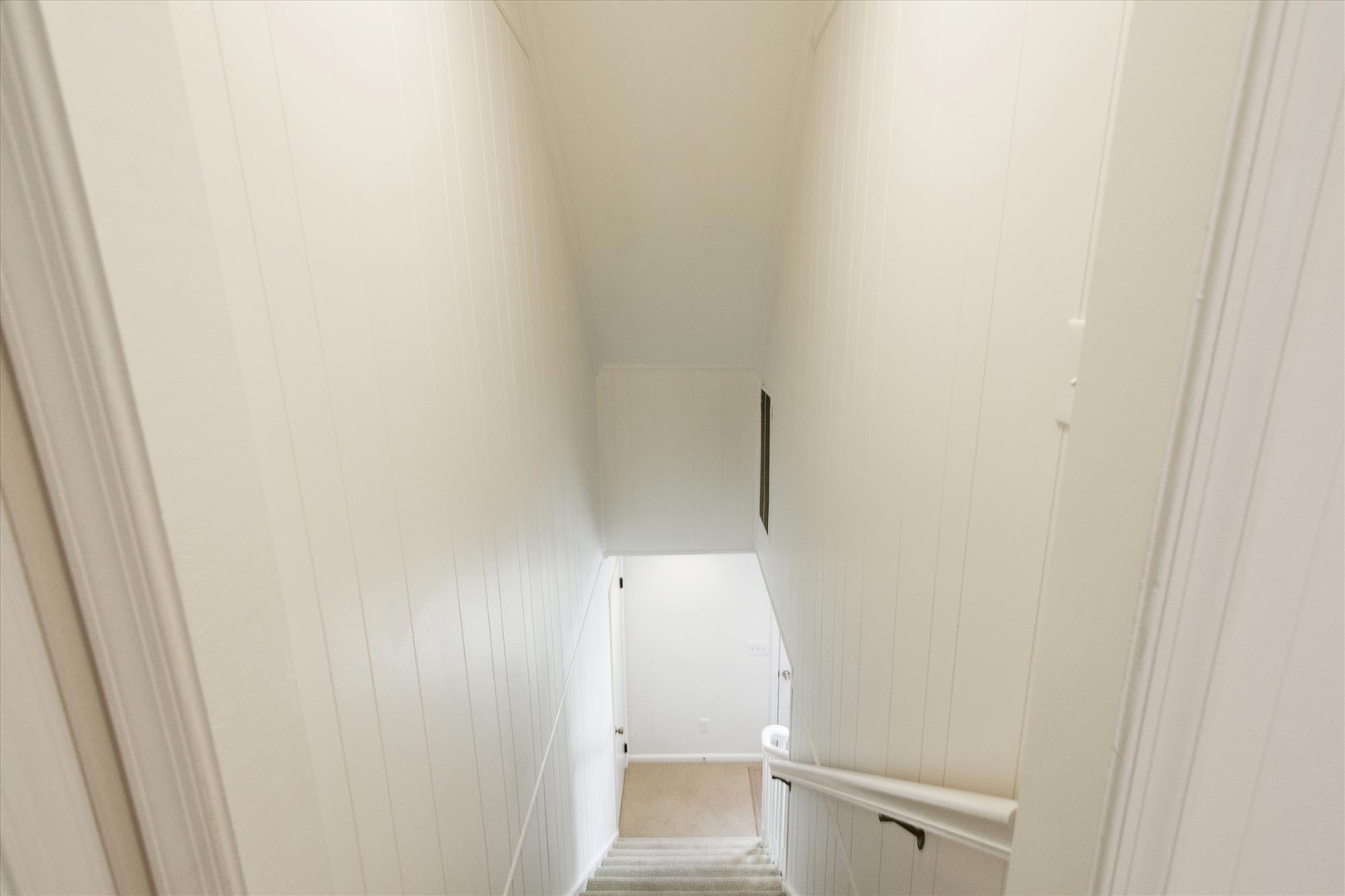 Elegant white wooden staircase with classic paneling leads you upstairs, creating a bright and welcoming atmosphere in your home away from home.