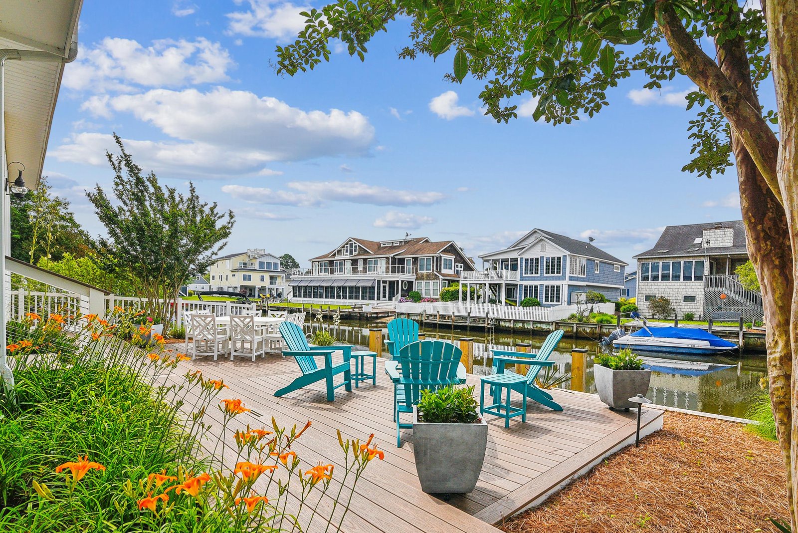 Relax in your own waterfront haven, where turquoise Adirondack chairs invite you to unwind on a private deck. Vibrant blooms and serene canal views frame a peaceful retreat perfect for morning coffee or sunset gatherings.