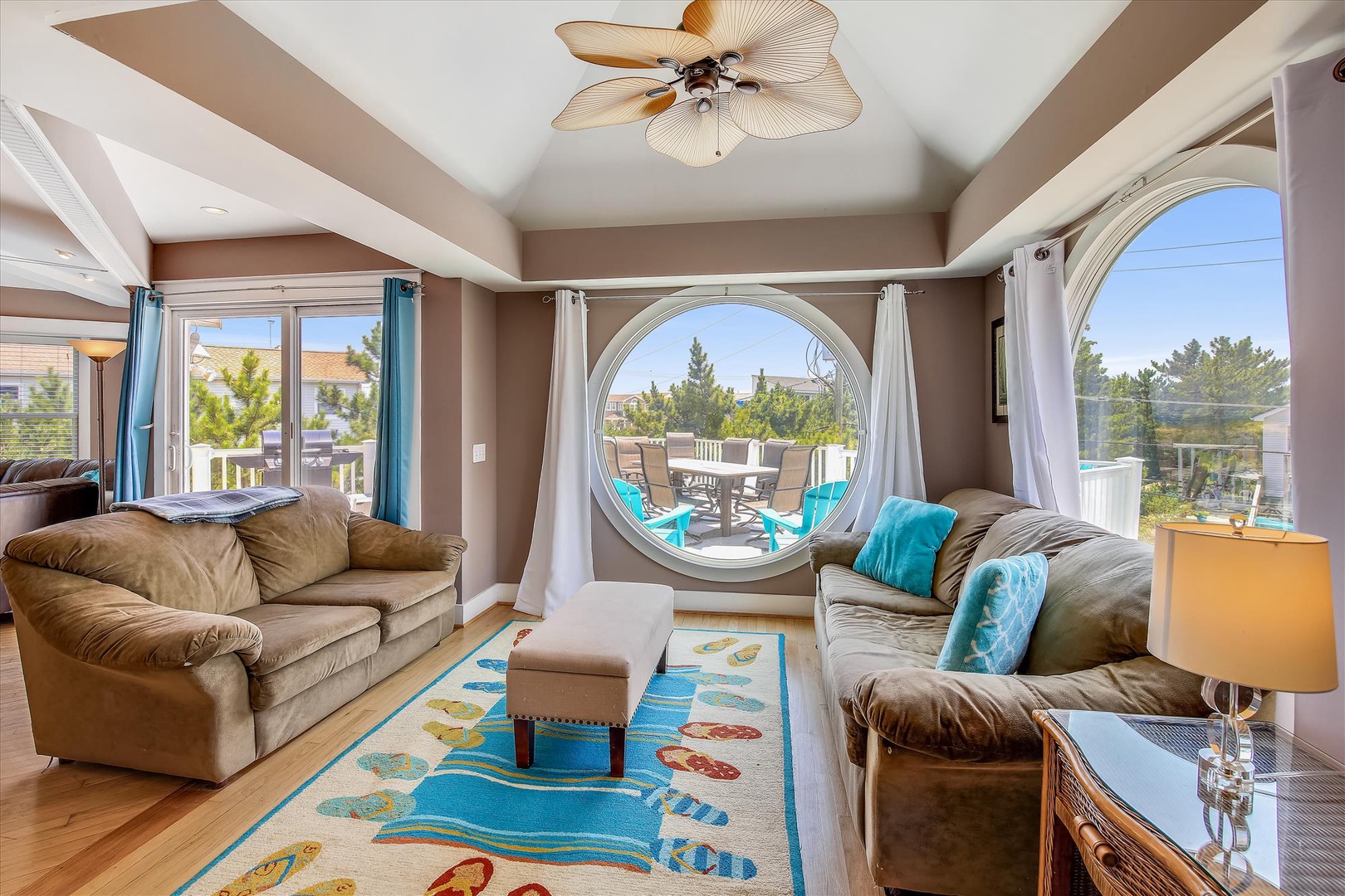 Relax in this inviting living room, where plush sofas and coastal charm surround you. Step through the unique round window onto your private deck overlooking trees and neighboring rooftops.