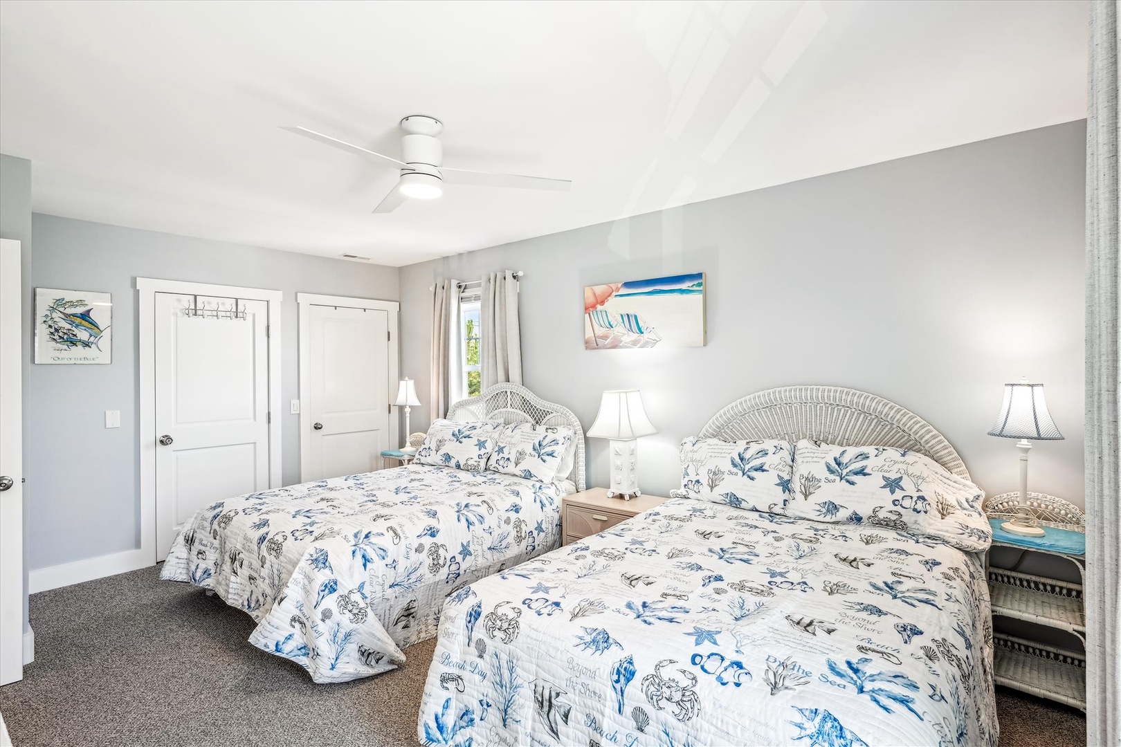 Rest easy in your coastal retreat with two inviting beds dressed in nautical linens, warm lighting, and a gentle ceiling fan to keep things comfortable.