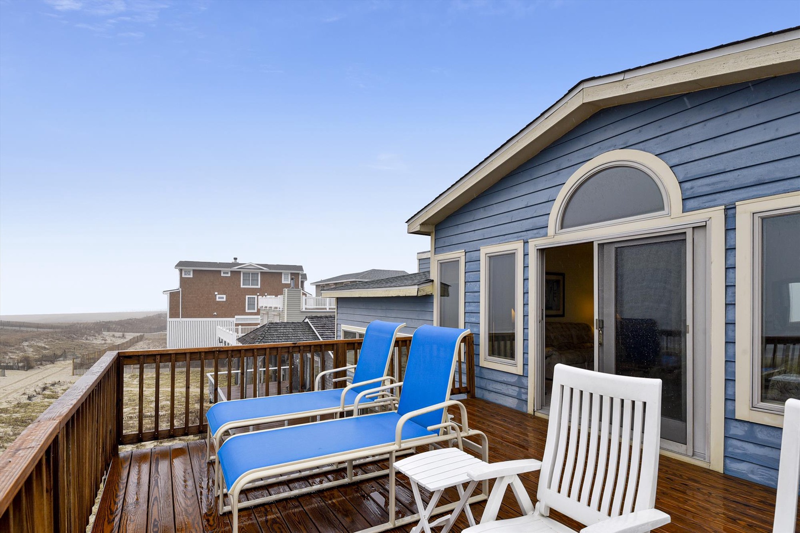 Relax on your private deck with comfortable loungers, taking in coastal views under the clear blue sky.