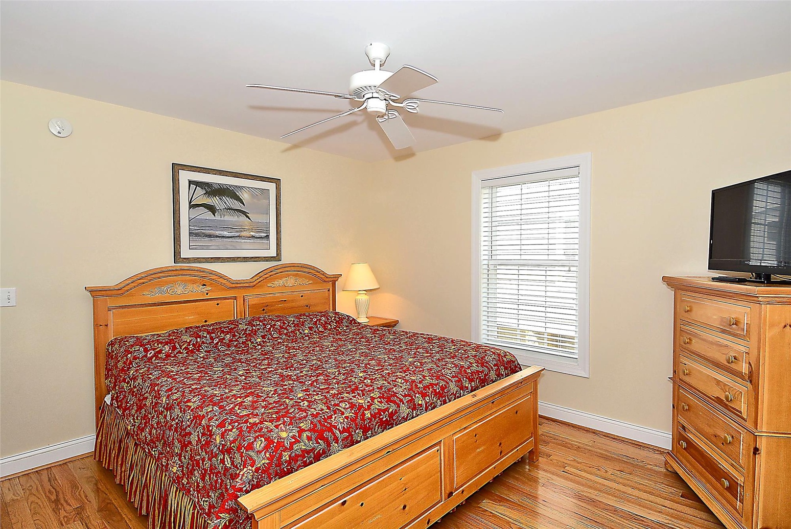 Unwind in your bright, cheerful bedroom with comfortable bedding, polished hardwood floors, and a gentle ceiling fan overhead—your coastal retreat awaits.
