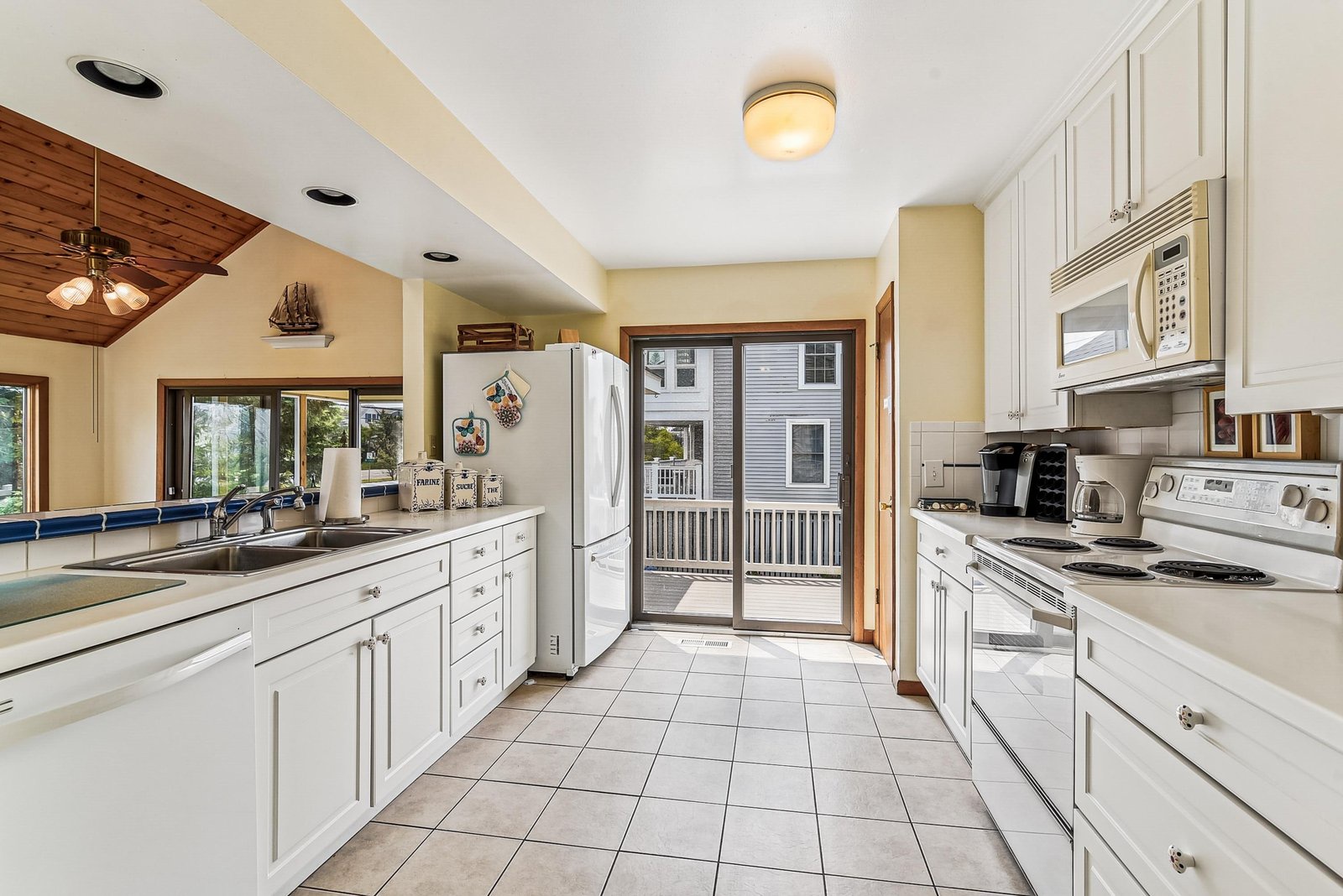 Step into your spacious kitchen with gleaming white cabinetry, ample prep space, and modern appliances ready for your morning coffee or home-cooked meals. Glass doors open to a private deck beyond.