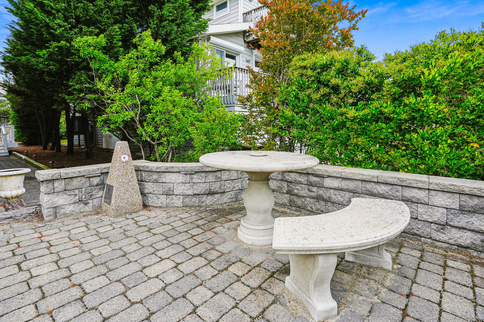 A charming stone patio surrounded by lush greenery and seasonal foliage, offering a peaceful spot to relax outdoors during your stay.