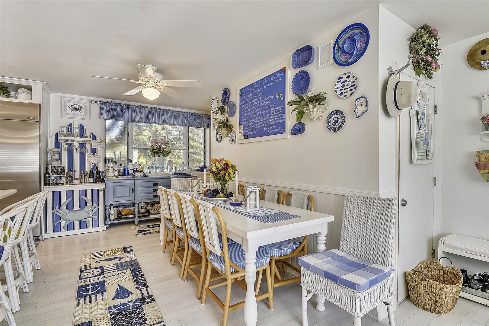 This charming coastal-themed kitchen and dining area showcases blue-accented decor, a welcoming farmhouse table, and all the comforts you'll need to prepare and enjoy delicious vacation meals together.