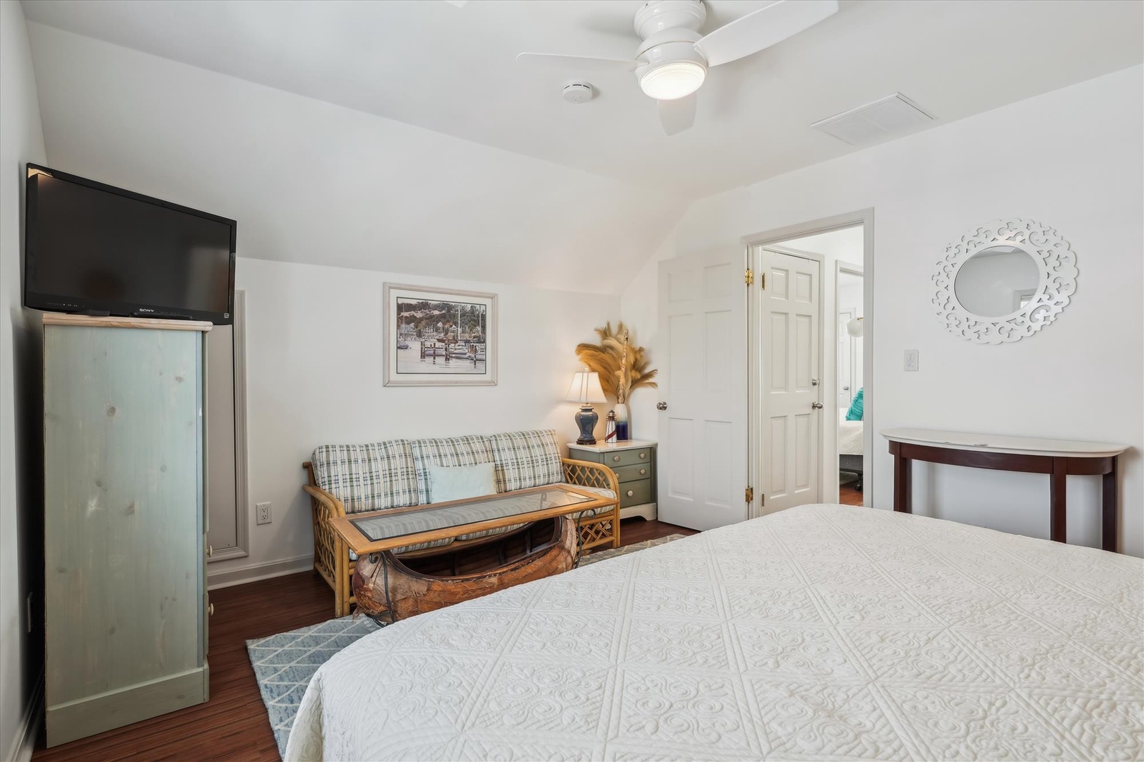 Your bright, serene bedroom features a plush bed, warm hardwood floors, and coastal accents. Relax on the bench sofa or catch up on your favorite shows with the flat-screen TV.