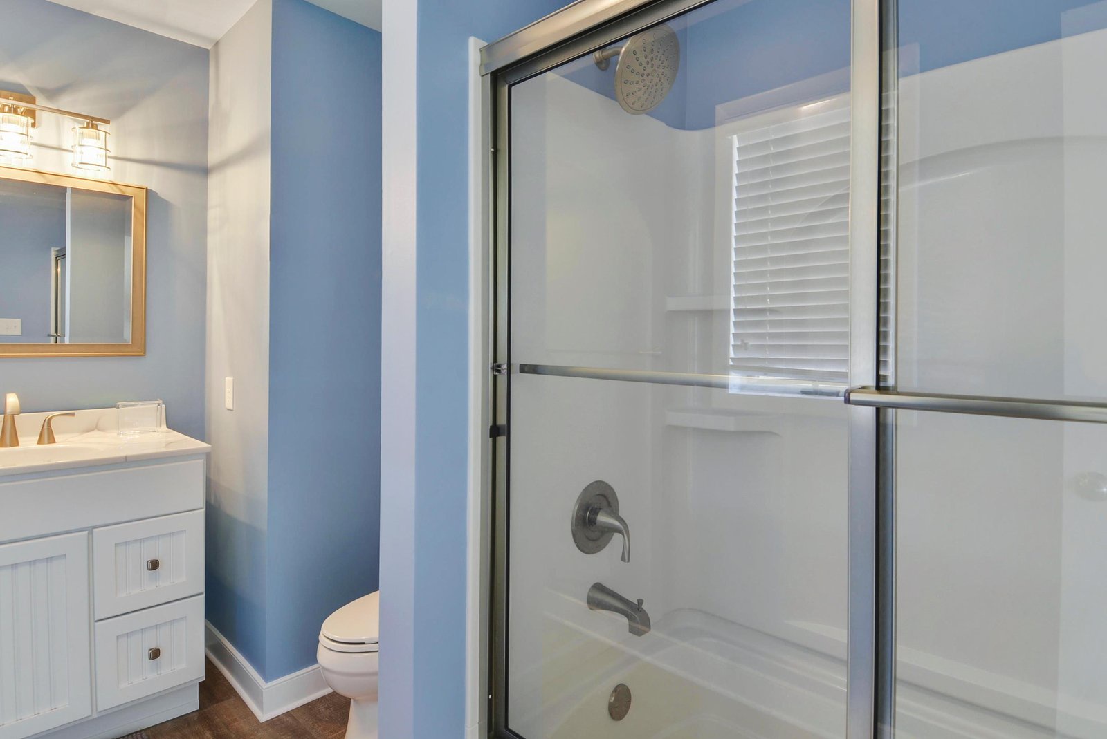 Slip into your clean, modern bathroom with soothing blue tones, a sleek glass-enclosed shower, and fresh white fixtures that make your morning routine feel effortless.
