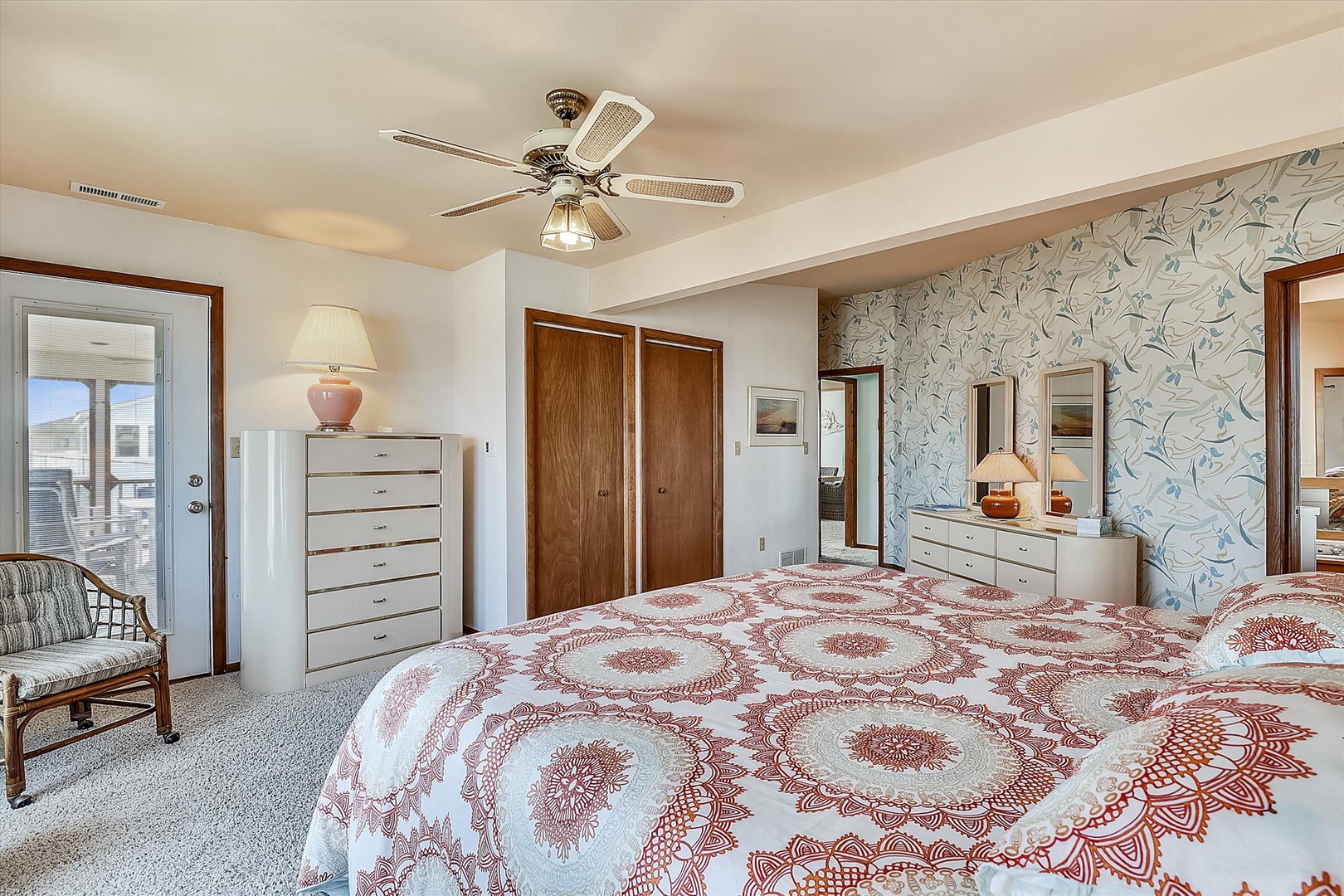 Unwind in this spacious bedroom featuring a plush king-size bed, elegant accent wall, and abundant natural light. Your private retreat offers ceiling fan, ample closet space, and cozy seating by the window.