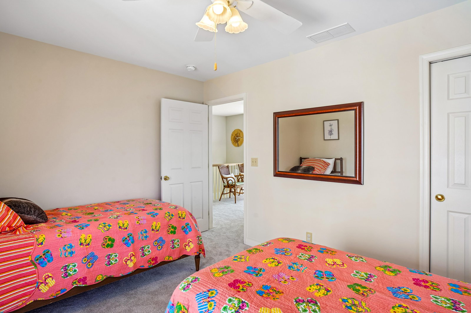 Two cozy beds await with cheerful linens and soft carpet underfoot. Your ceiling fan ensures comfort as you unwind in this bright, welcoming space.