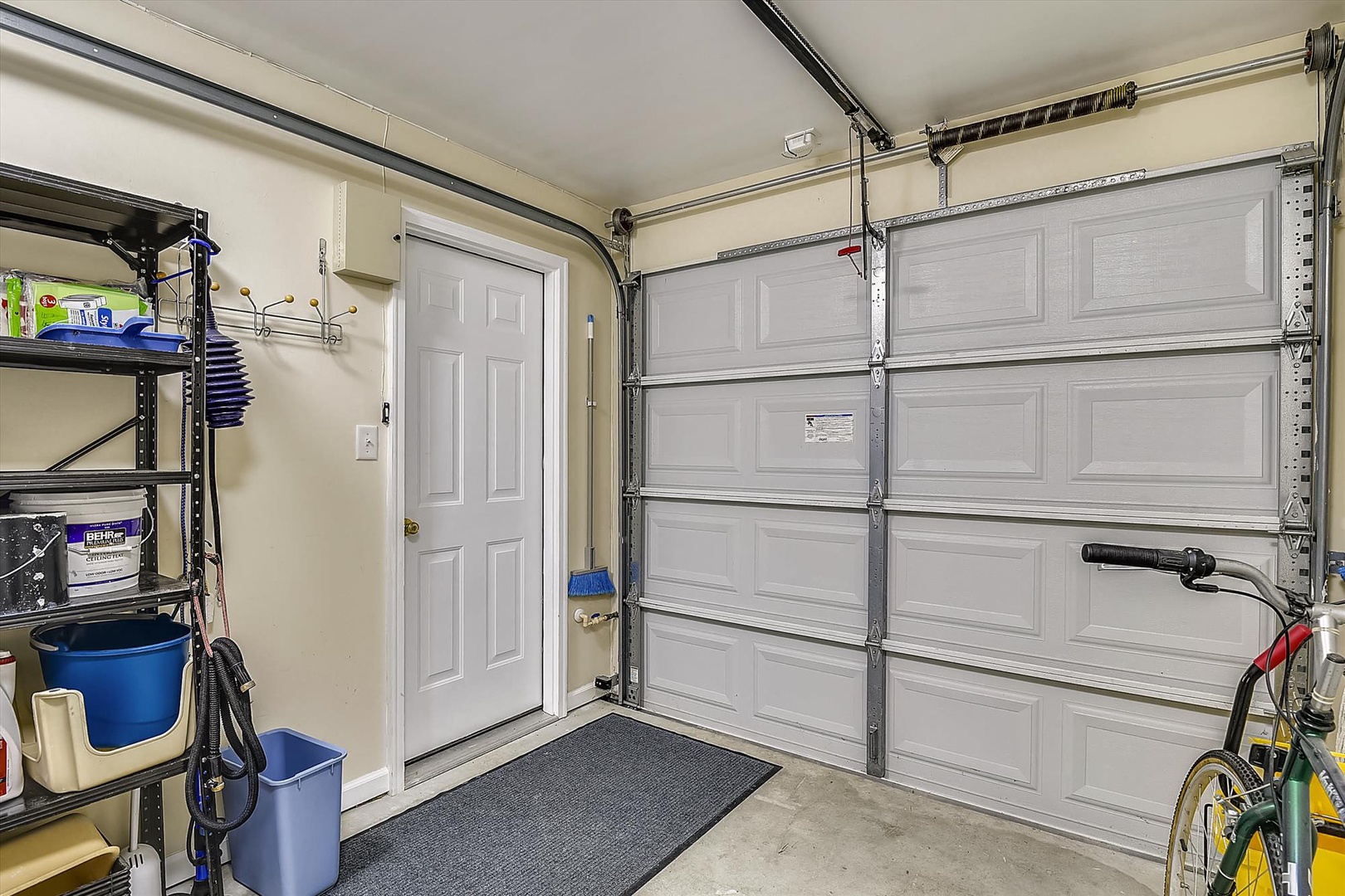 Spacious, climate-controlled garage with organized storage shelving, interior access door, and secure overhead door system—perfect for safely parking your vehicle and storing sports or beach gear.
