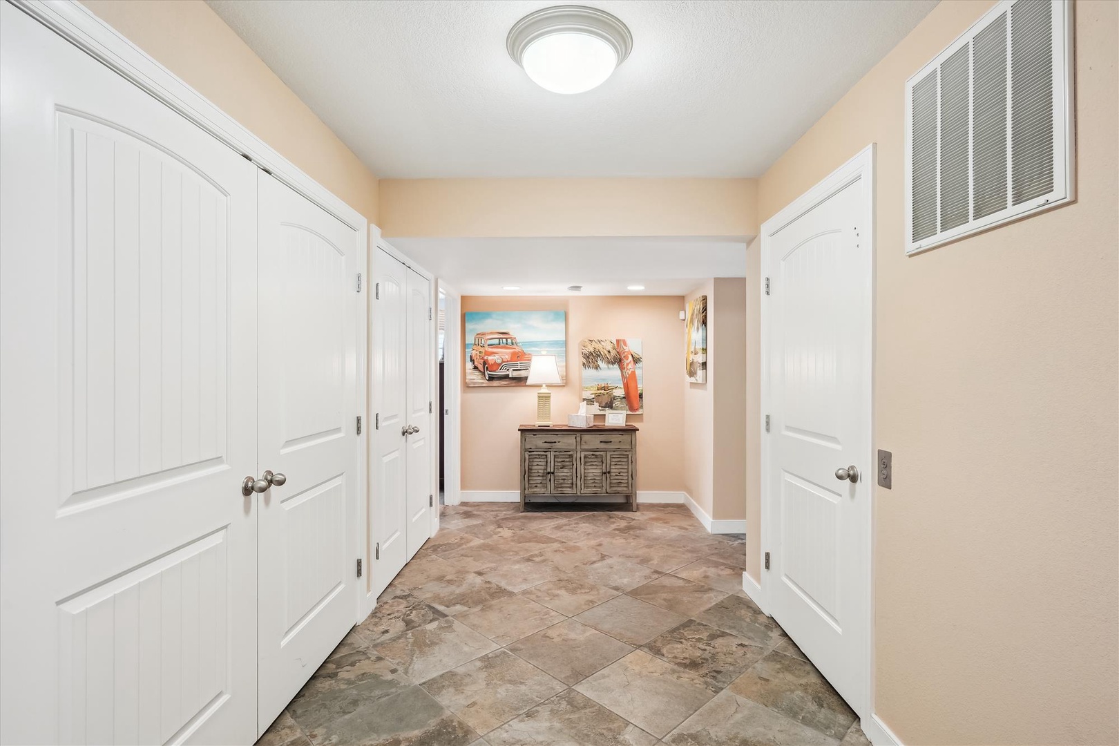 A welcoming hallway greets you with warm coastal décor, tasteful artwork, and plenty of storage space behind classic white doors, setting a comfortable tone for your stay.