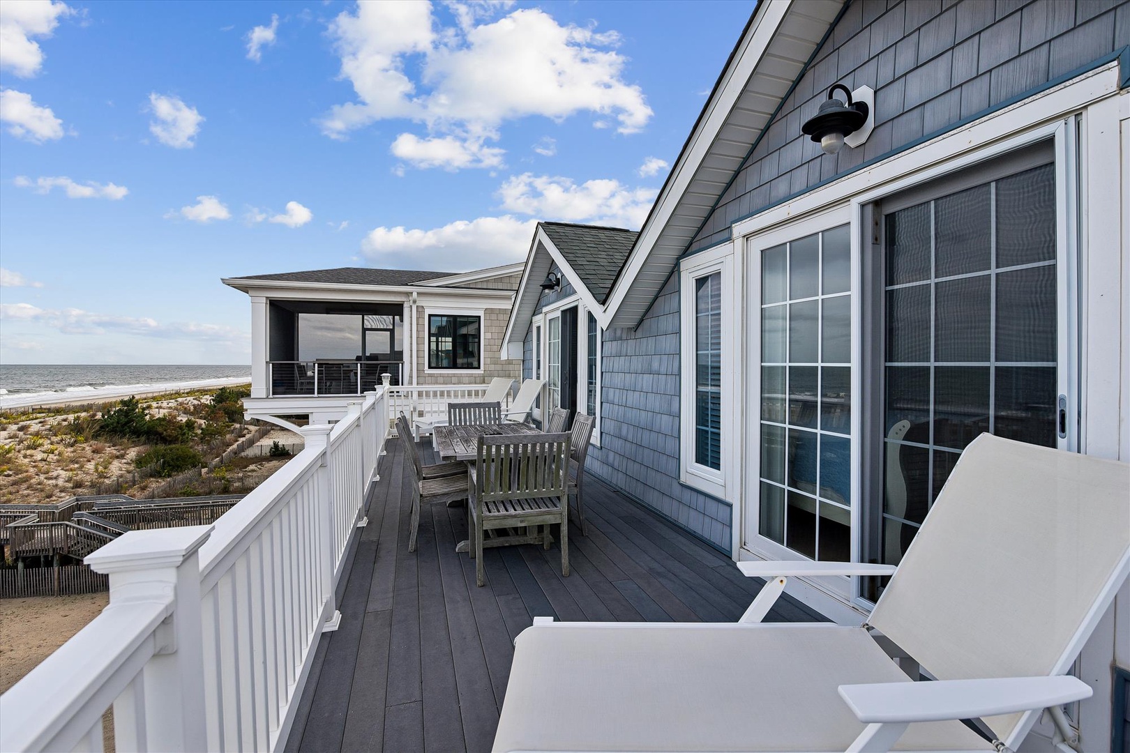 This property features a spacious beachfront deck with coastal architecture and direct access to sandy shores, offering an ideal setting for a relaxing seaside escape.