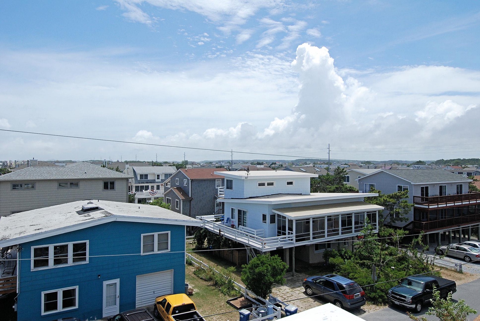 Coastal neighborhood featuring beach houses and residential properties situated near the shore, with residential streets and nearby community amenities visible.