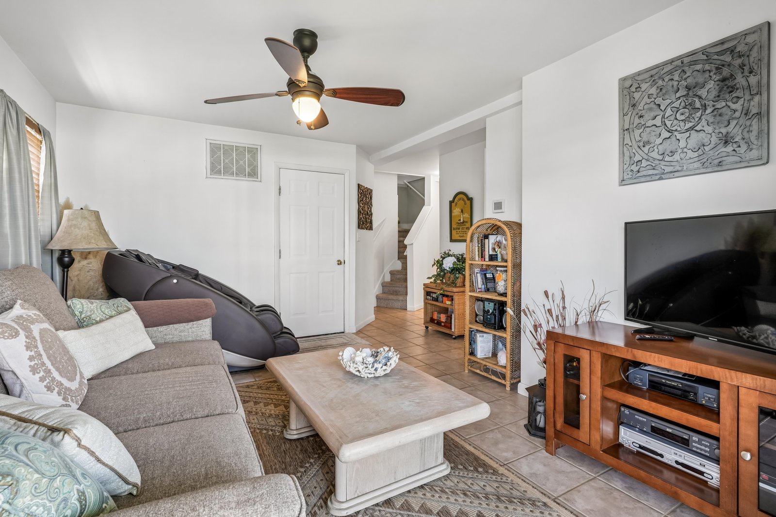 Settle into the inviting living room where coastal charm meets comfort. Relax on plush seating, enjoy your favorite shows, and feel the cool breeze from the ceiling fan overhead.