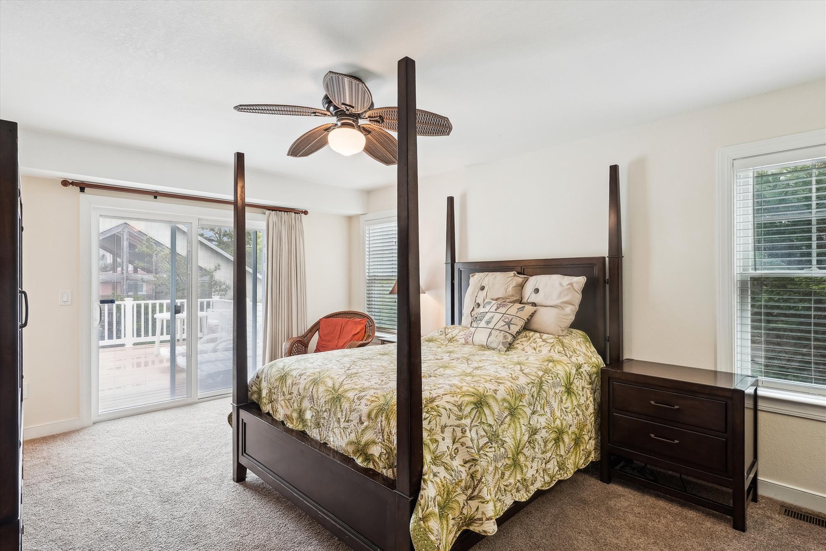 Sink into your plush four-poster bed with tropical-inspired linens. Sliding glass doors open to a private balcony, while ceiling fan and soft bedside lighting create cozy ambiance.