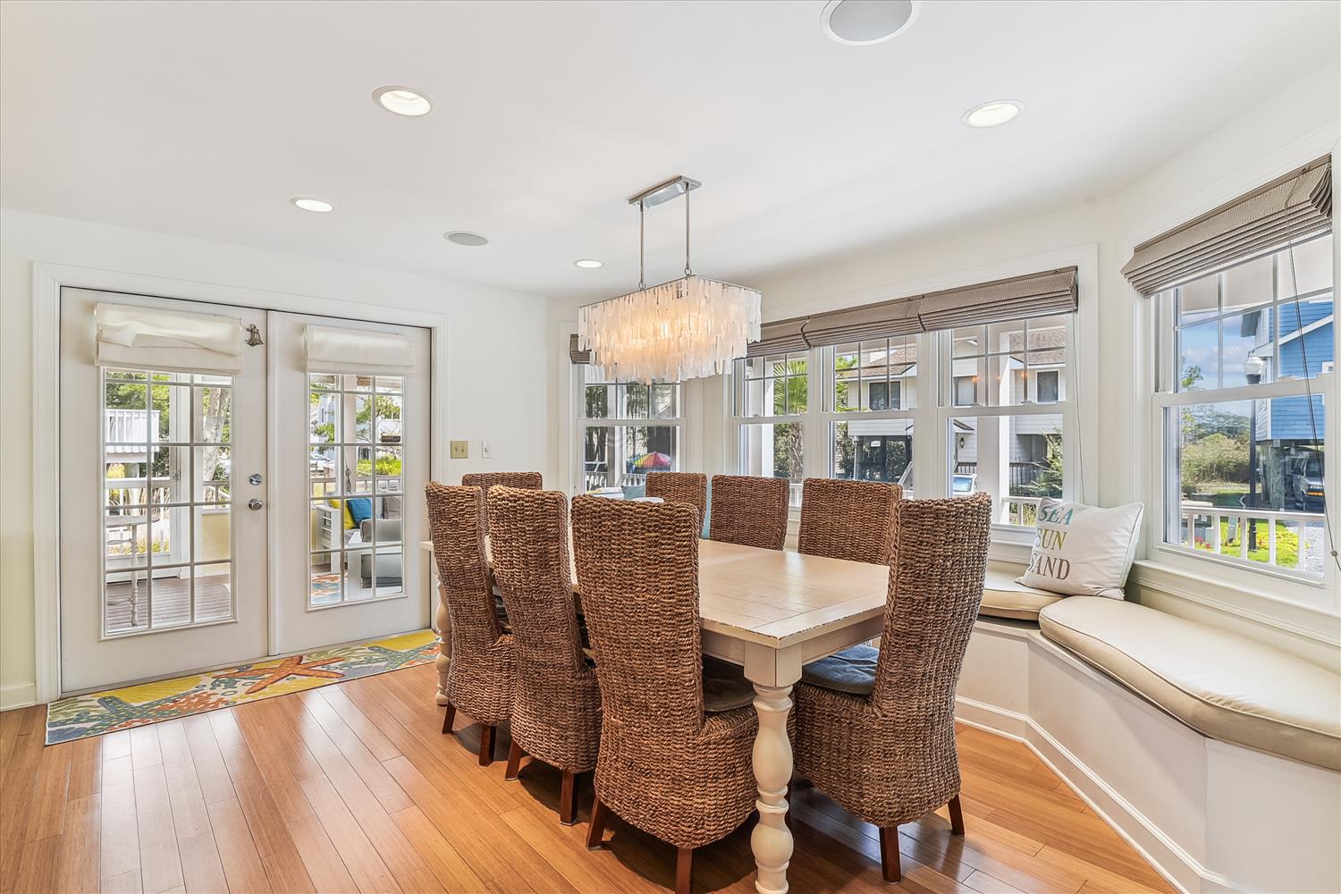 Gather your group around this sun-drenched dining table with textured seating, where coastal charm meets comfort. French doors open to your private outdoor space, inviting easy flow for meals and conversation.