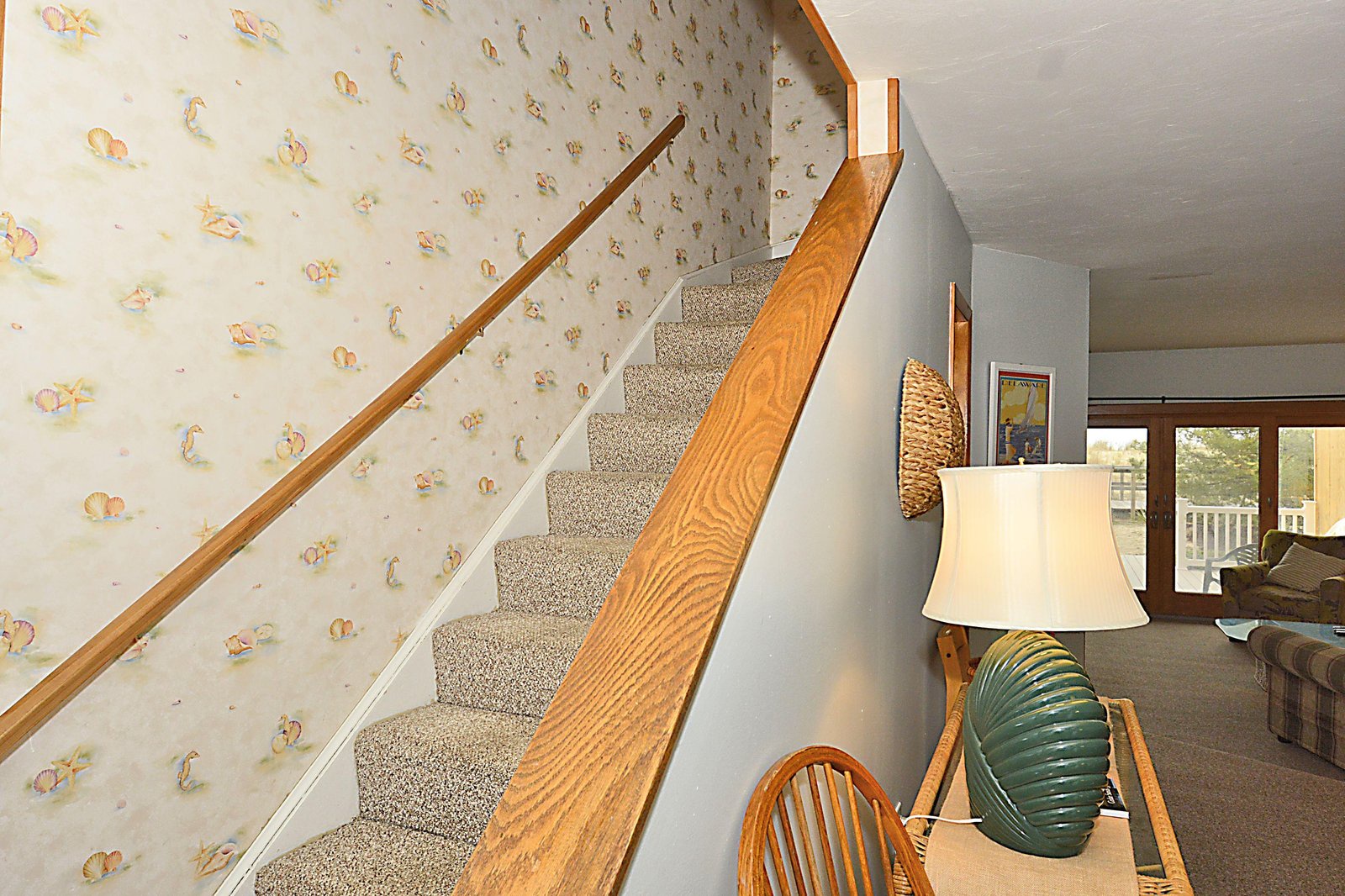 Carpeted stairs and a wooden banister connect the levels of your vacation home, with the living area just beyond the landing.