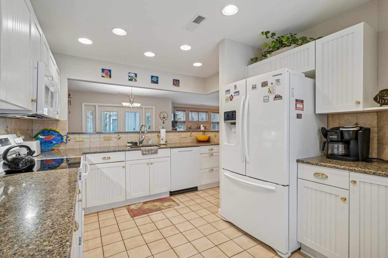 Your spacious full kitchen features everything you need for home-cooked meals—granite counters, white cabinetry, modern appliances, and plenty of prep space to gather and create together.