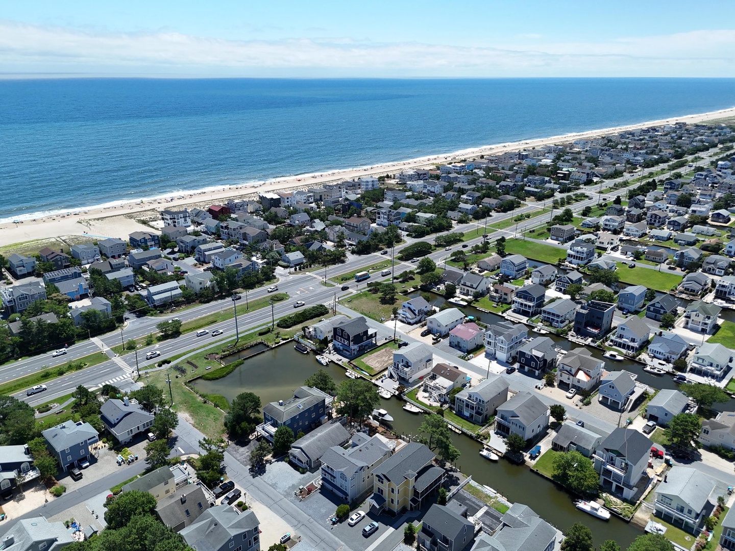 Aerial view of a coastal neighborhood with direct beach access, waterfront canals, and ocean views just steps away from the property.