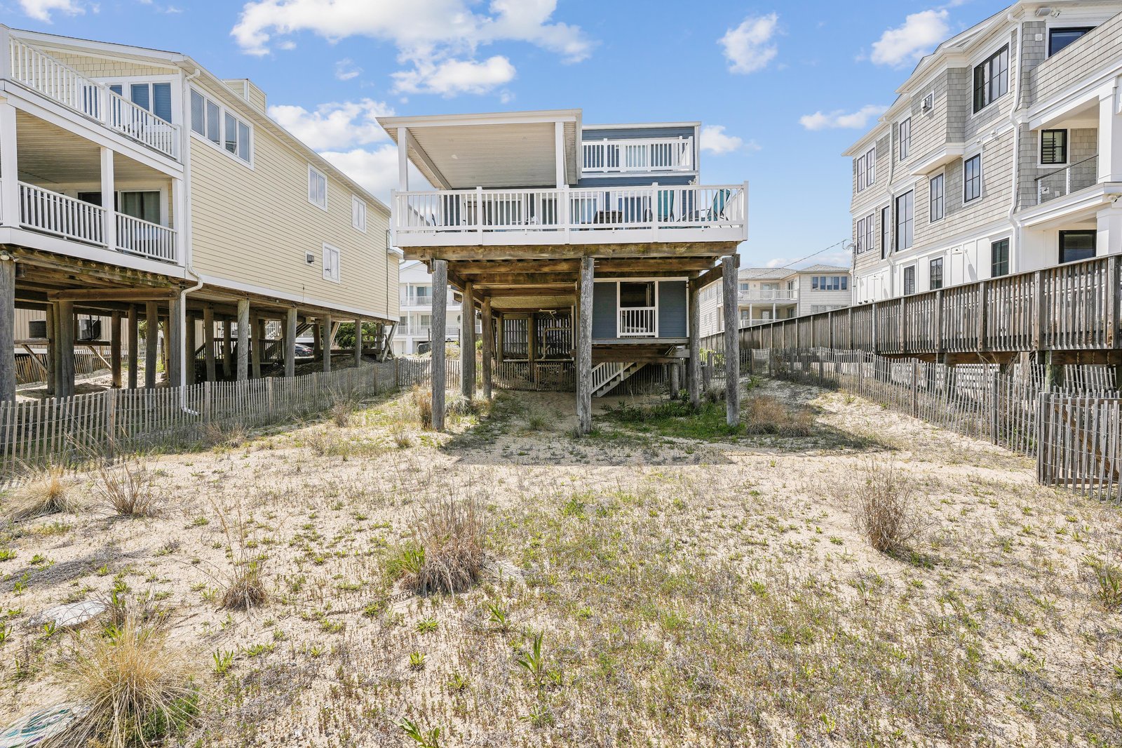 Coastal property elevated on sturdy pilings with beachside access, surrounded by neighboring homes in a quiet residential beach community.