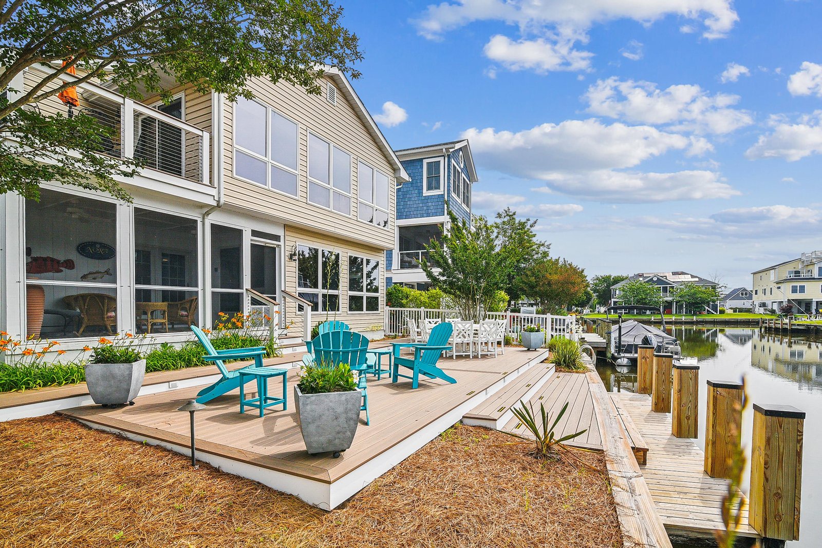 Waterfront property featuring a private deck with Adirondack chairs and direct canal access with boat dock, located in a quiet residential neighborhood.