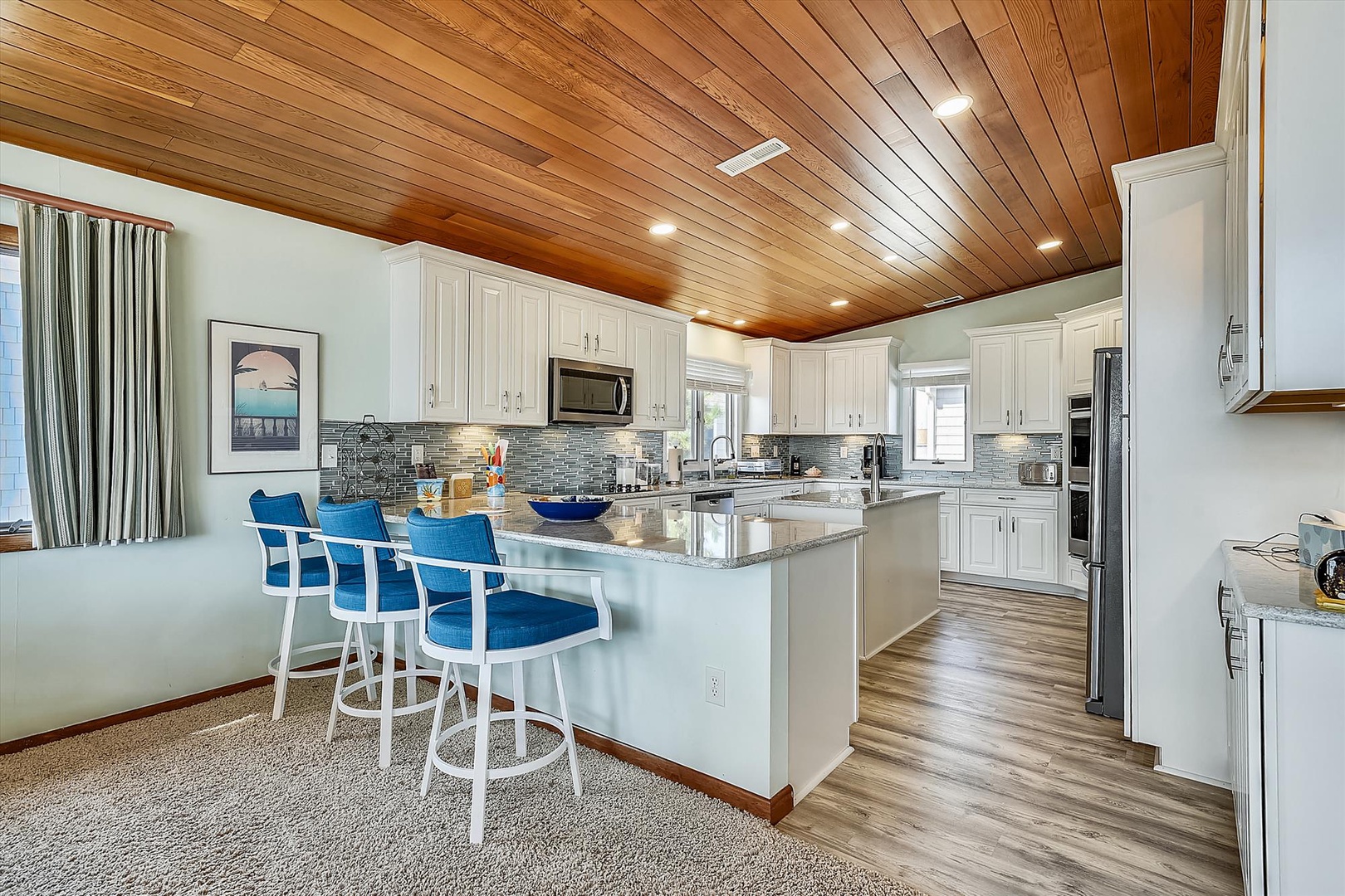 Gather around this inviting kitchen island with three cozy bar stools, where you can sip morning coffee under stunning wood-paneled ceilings or prep meals on granite countertops.