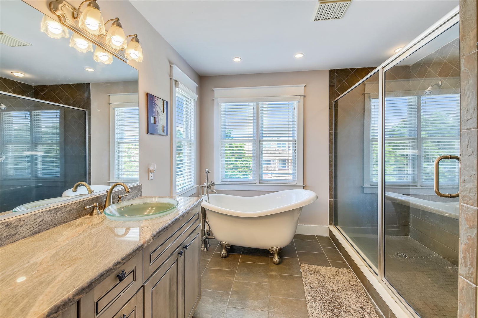 Sink into the elegant clawfoot tub and let your cares melt away in this spa-like bathroom with stylish fixtures, dual vanities, and a spacious glass-enclosed shower.