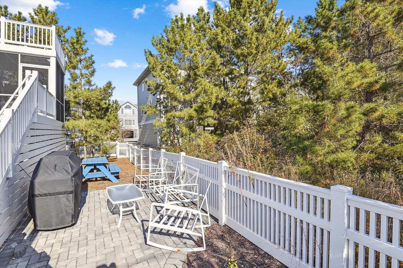Enjoy fresh air and sunshine on your private patio, complete with a gas grill, cozy seating, and a picnic table for alfresco meals surrounded by lush greenery.