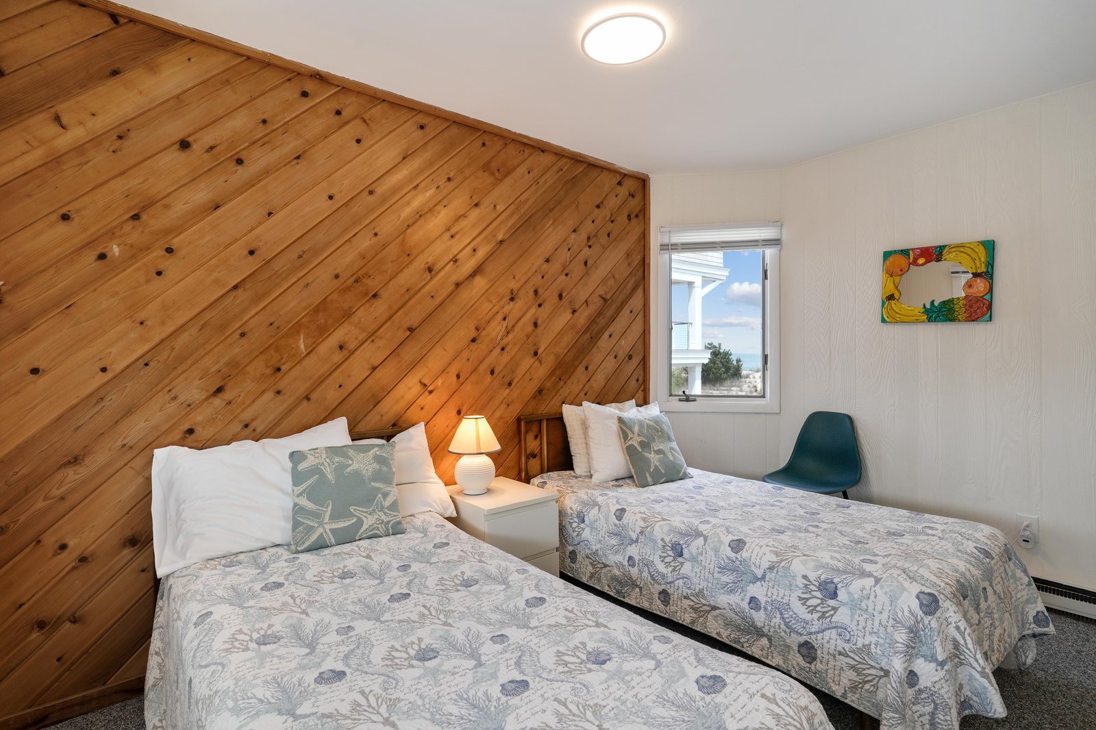Unwind in your coastal retreat with twin beds dressed in soft linens, warmed by natural knotty pine walls that bring a touch of rustic charm to your seaside stay.