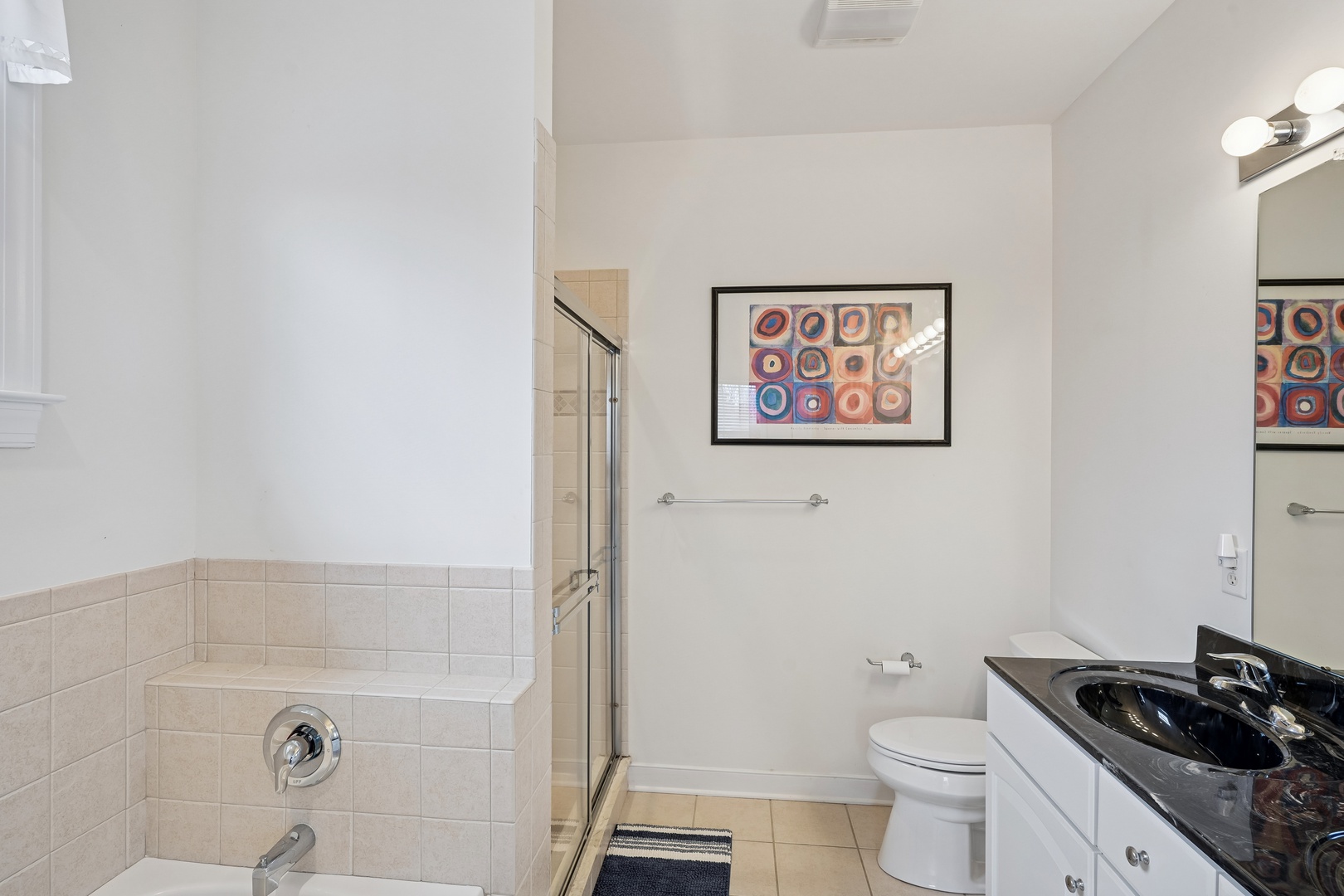 Refresh in your private bathroom featuring a modern glass shower, granite vanity, and thoughtful artwork to brighten your daily routine.