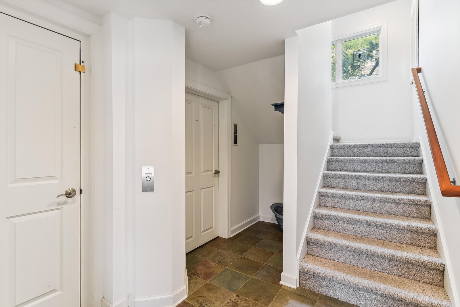 Step into your bright, welcoming entryway. Natural light streams through the window, guiding you upstairs to your comfortable retreat.