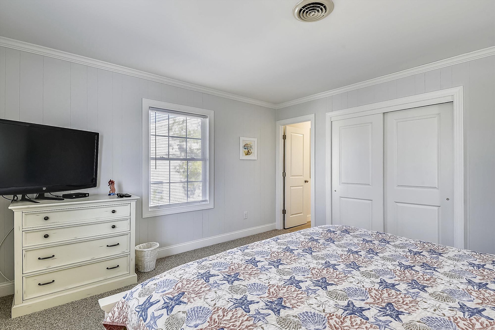 Step into your peaceful retreat with a plush bed, coastal-inspired linens, and soft carpeting underfoot. Your flat-screen TV awaits for cozy evenings in.