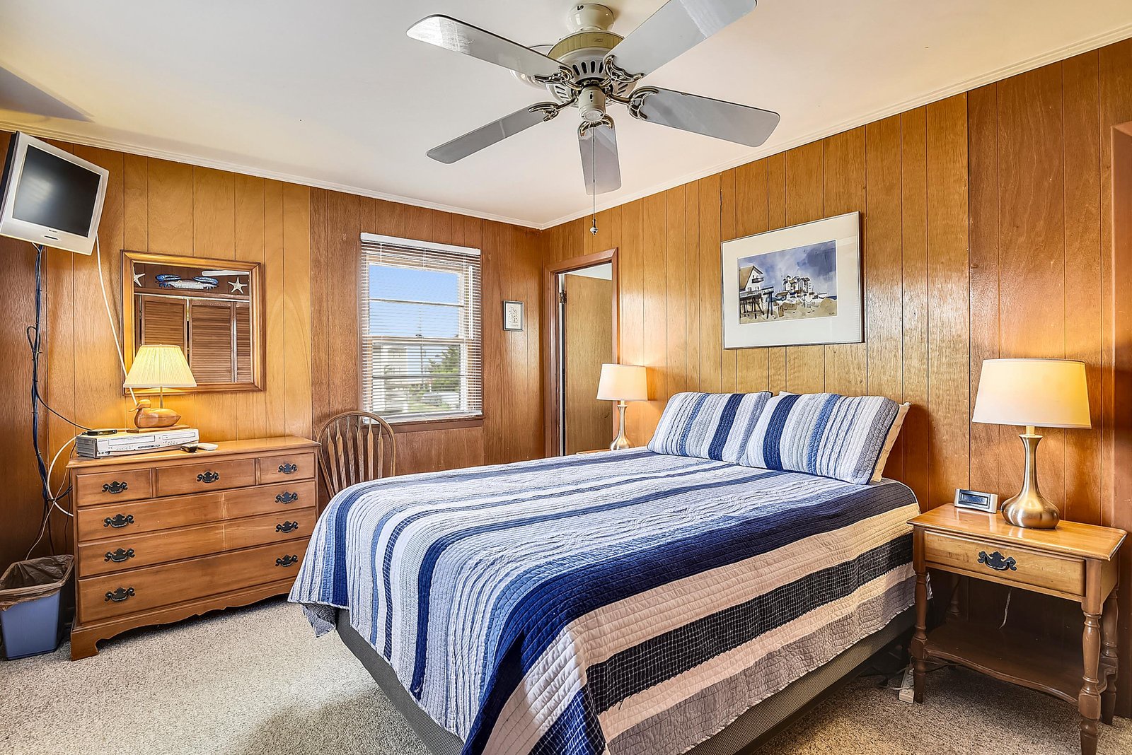 Sink into the plush comfort of your coastal retreat, where warm wood paneling and soft linens create the perfect beachside bedroom for restful nights.