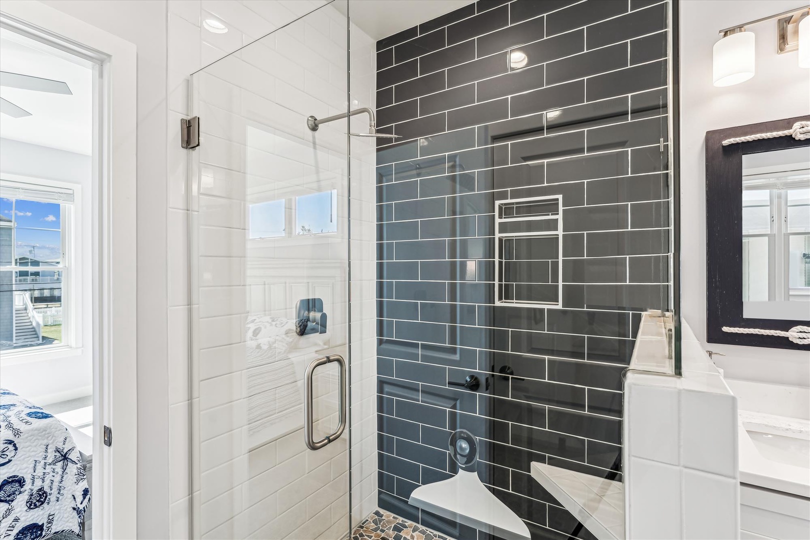 Refresh in your elegant glass-enclosed shower with sleek charcoal subway tiles and modern fixtures, perfectly complementing the bright bathroom.