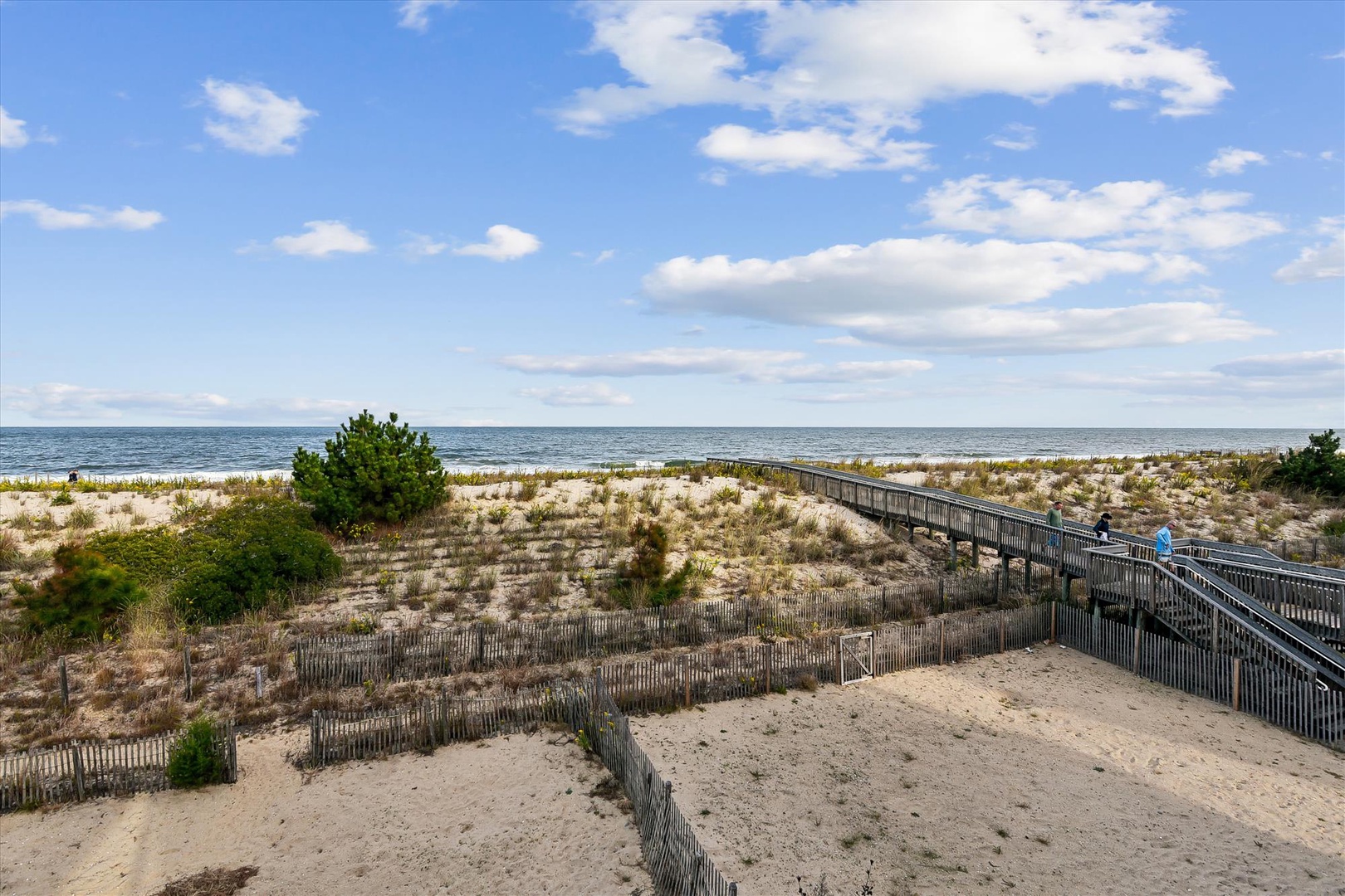 Scenic beachfront property with private boardwalk access leading through protected dunes to the sandy shore and ocean beyond.